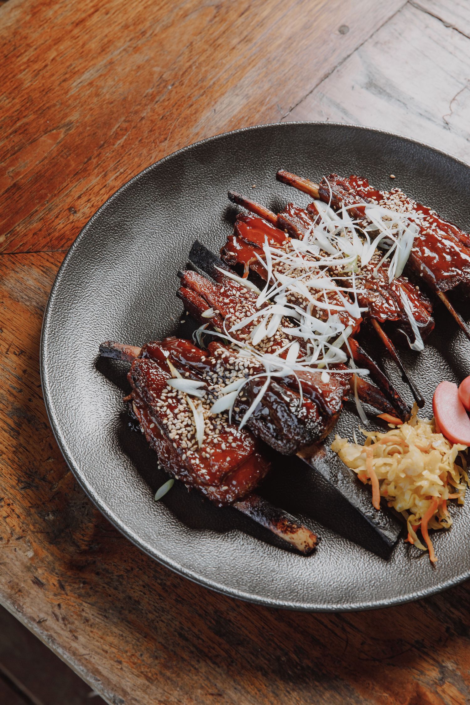 Coconut braised char siu venison ribs on plate with pickles and kimchi