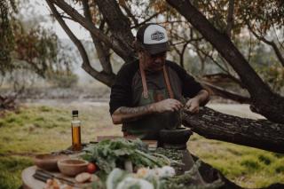 Chef Clayton Donovan standing at outdoor table prepping local ingredients