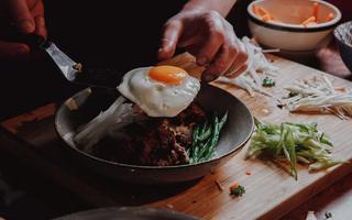 Venison Bi bim bap being plated with a fried egg