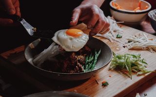 Venison Bi bim bap being plated with a fried egg
