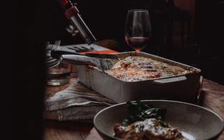 Venison Lasagne ready to be served, alongside a glass of red wine