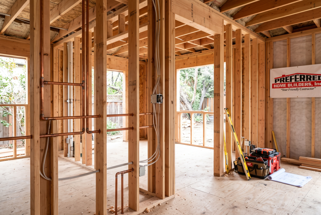 Capture the physical reality of a full-gut remodel—exposed framing, rough plumbing/electrical work, and structural changes.