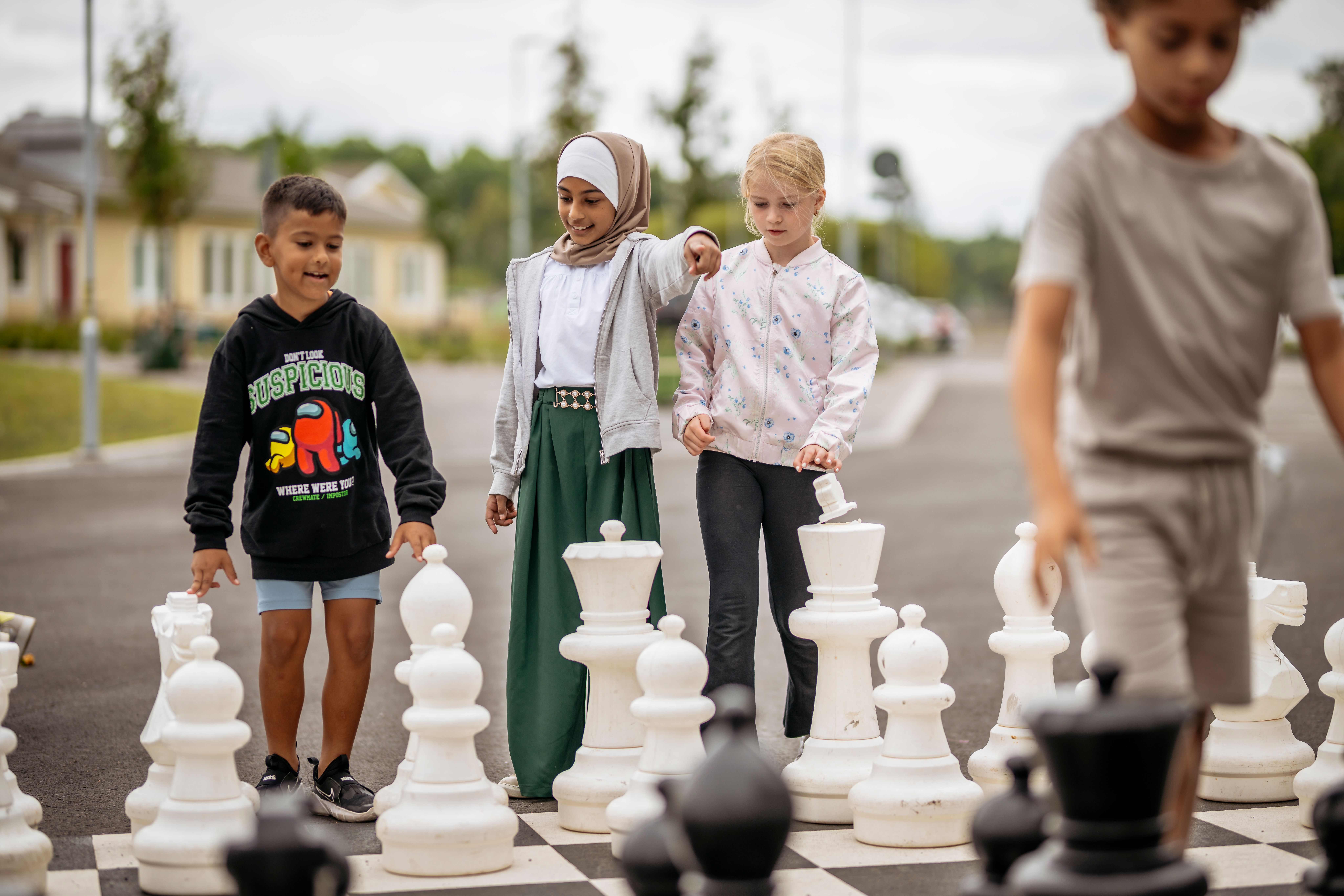 Barn spelar stort schack på gården