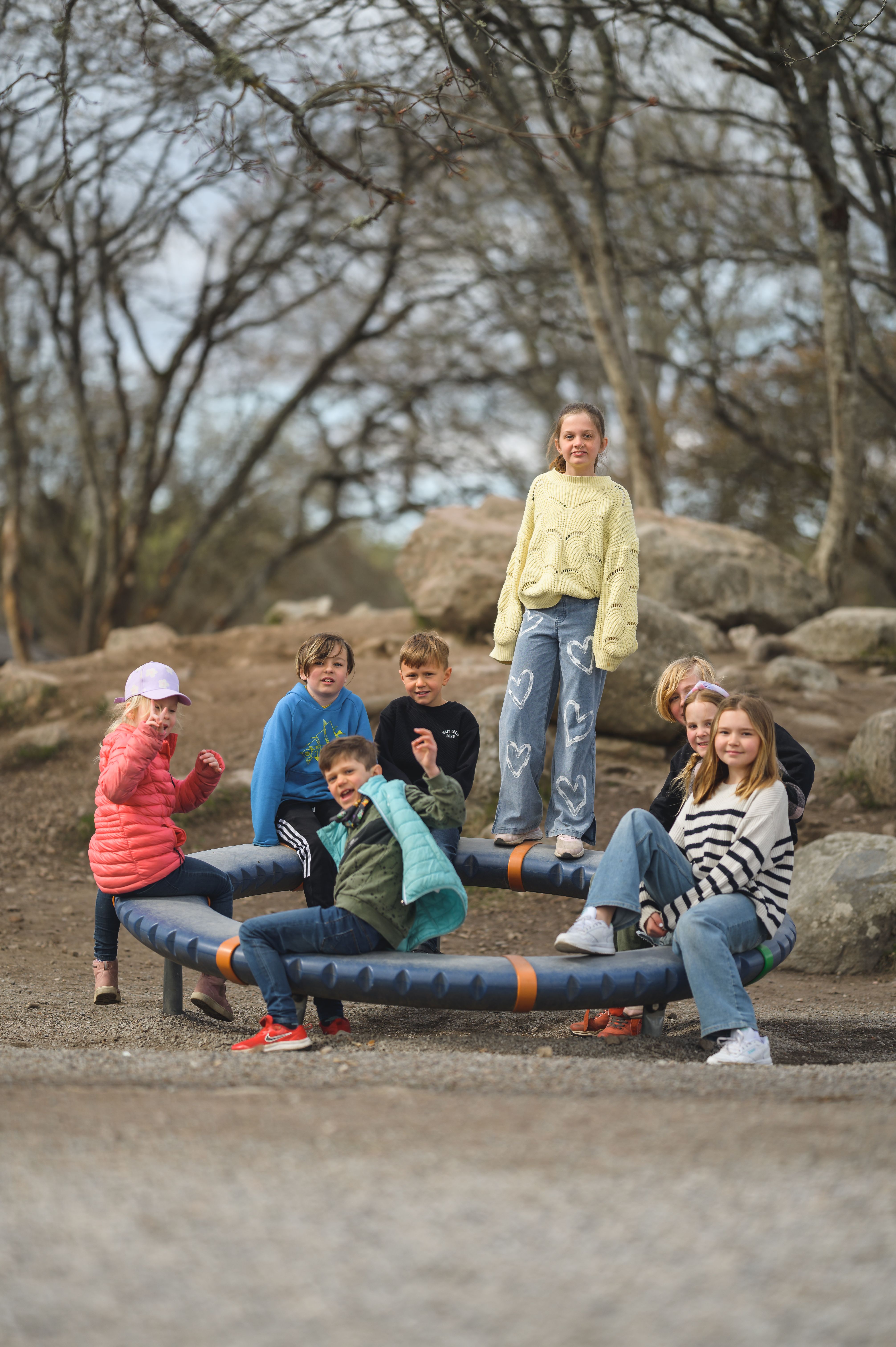 Sju barn leker utomhus vid en cirkel