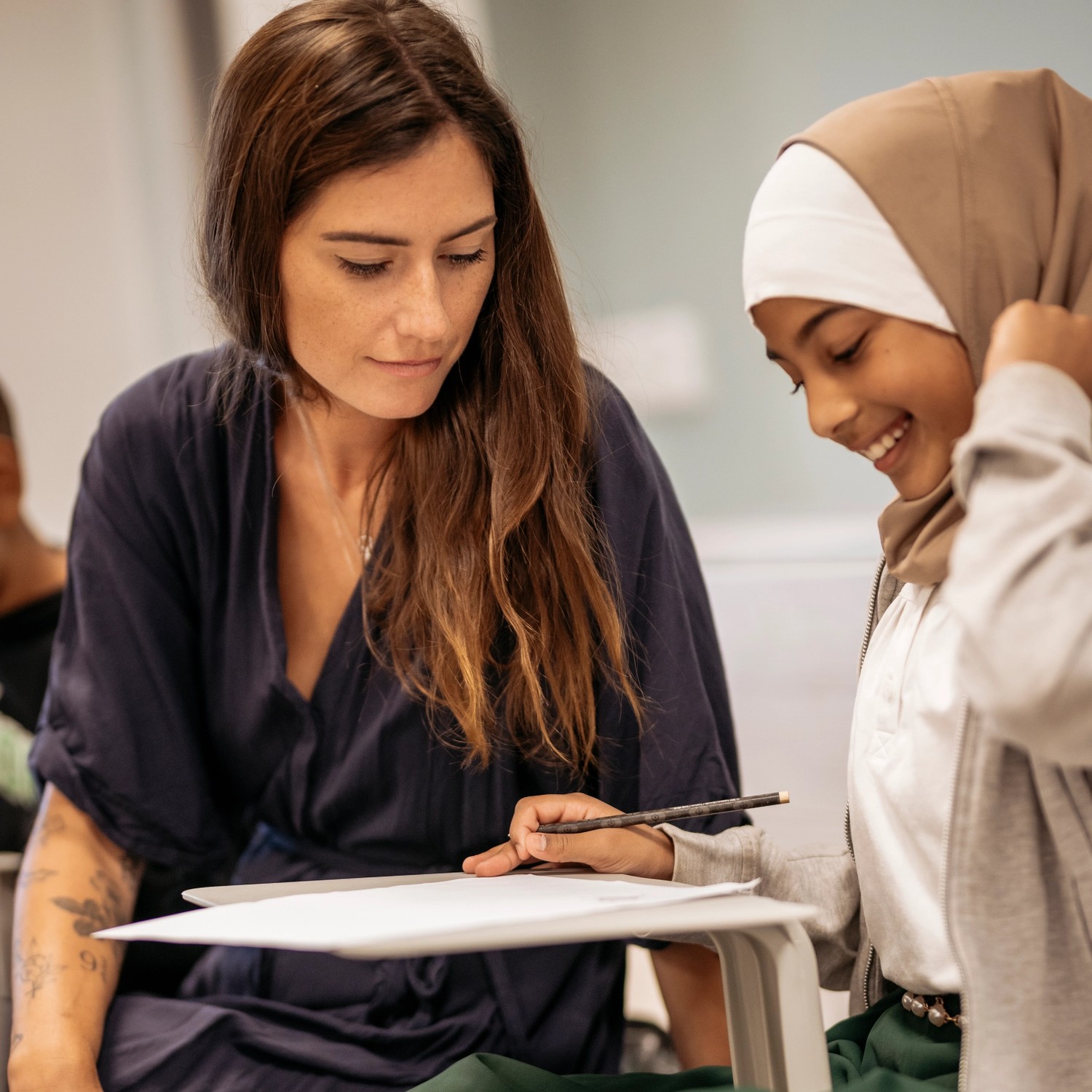 Lärare sitter tillsammans med en elev och går igenom en uppgift