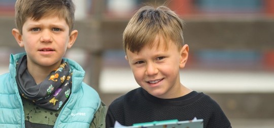 Två barn som ler och kollar in i kameran