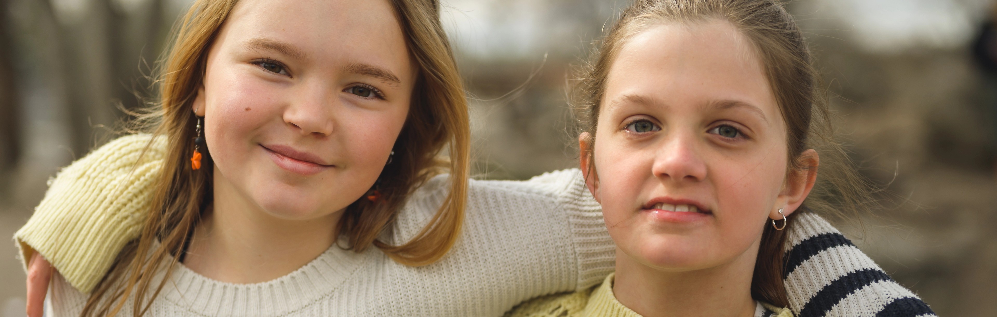 två tjejer håller varandra om axlarna utomhus