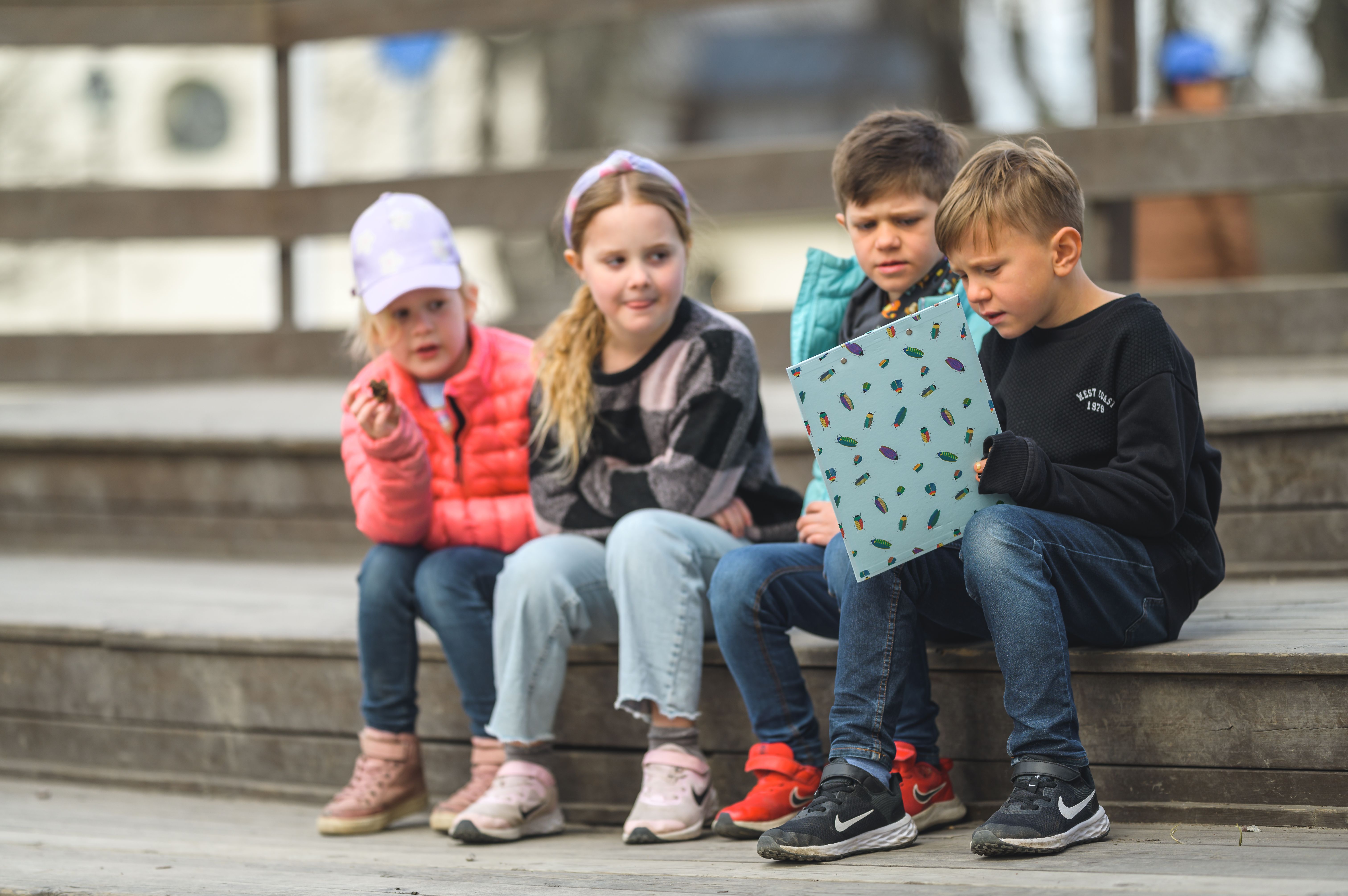 barn sitter utomhus med mapp som de tittar på