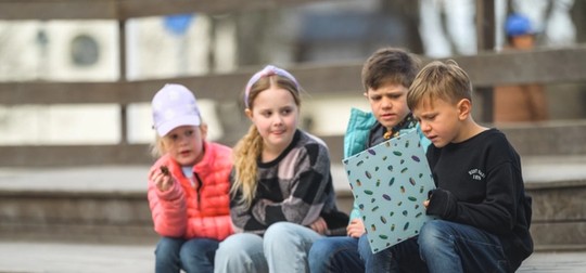 barn sitter utomhus med mapp som de tittar på