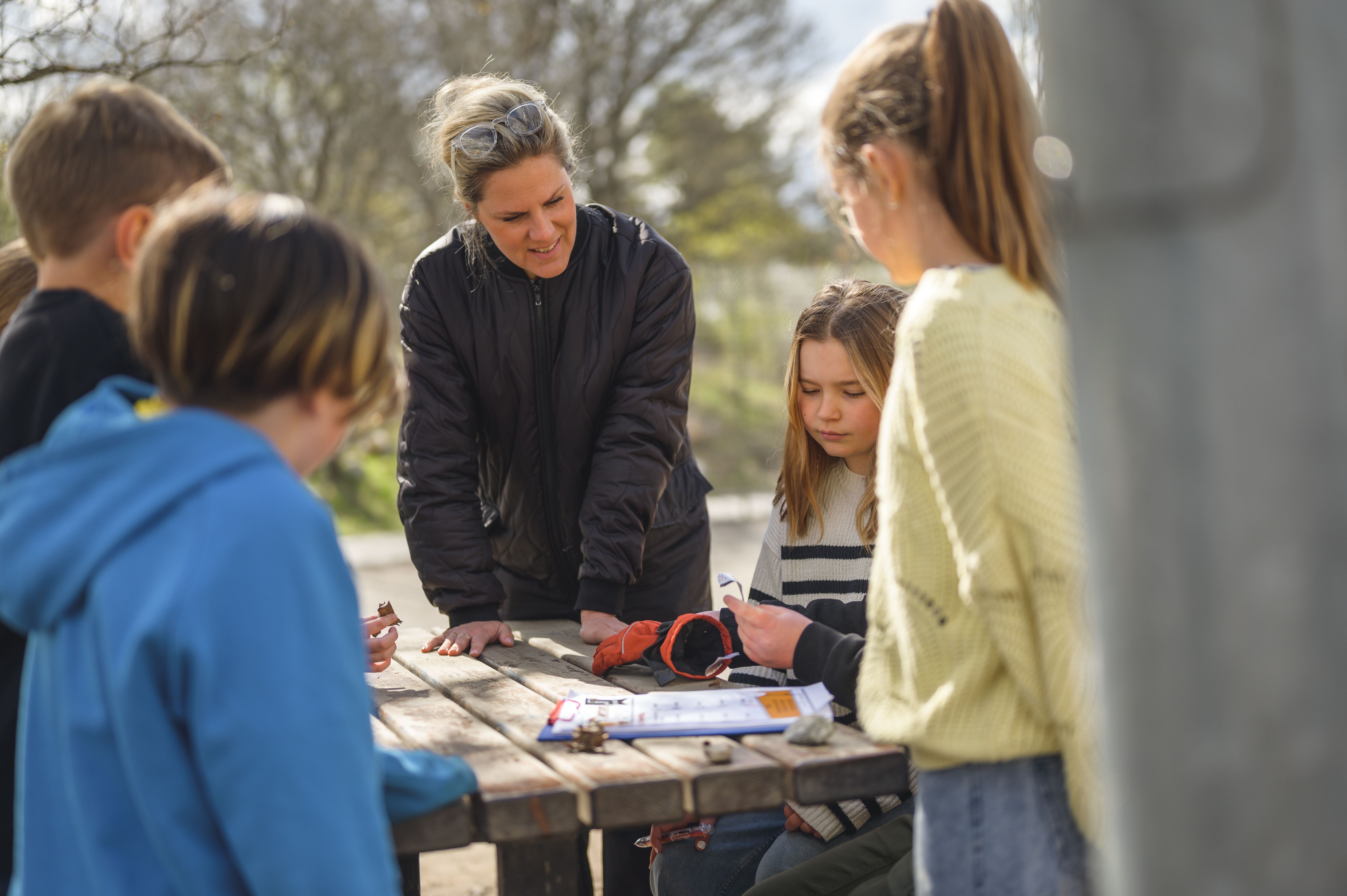 Grupp arbetar utomhus med lärare