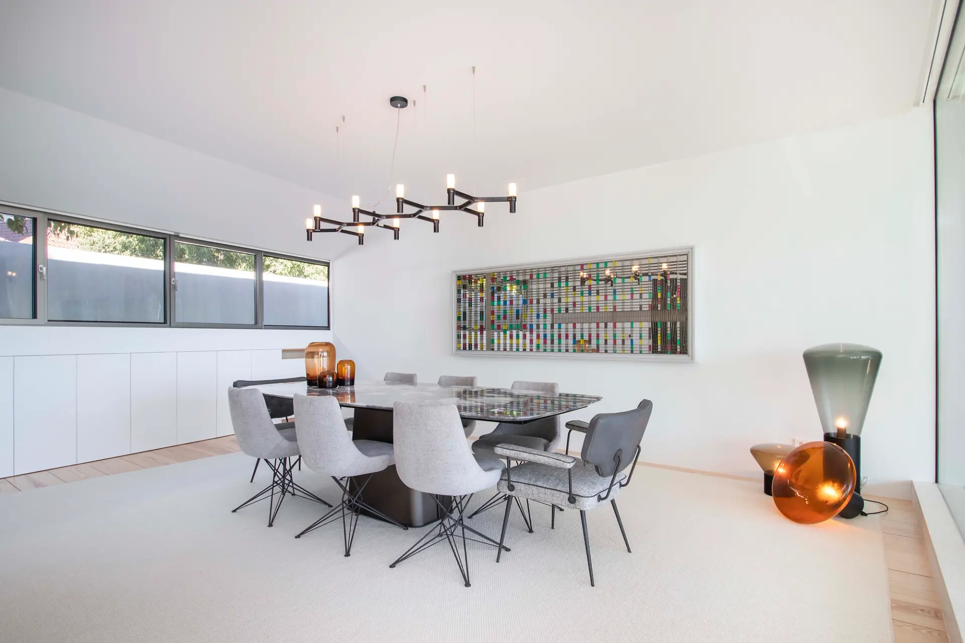 Sala de jantar decorada com mesa, cadeiras, iluminação decorativa e obra de arte