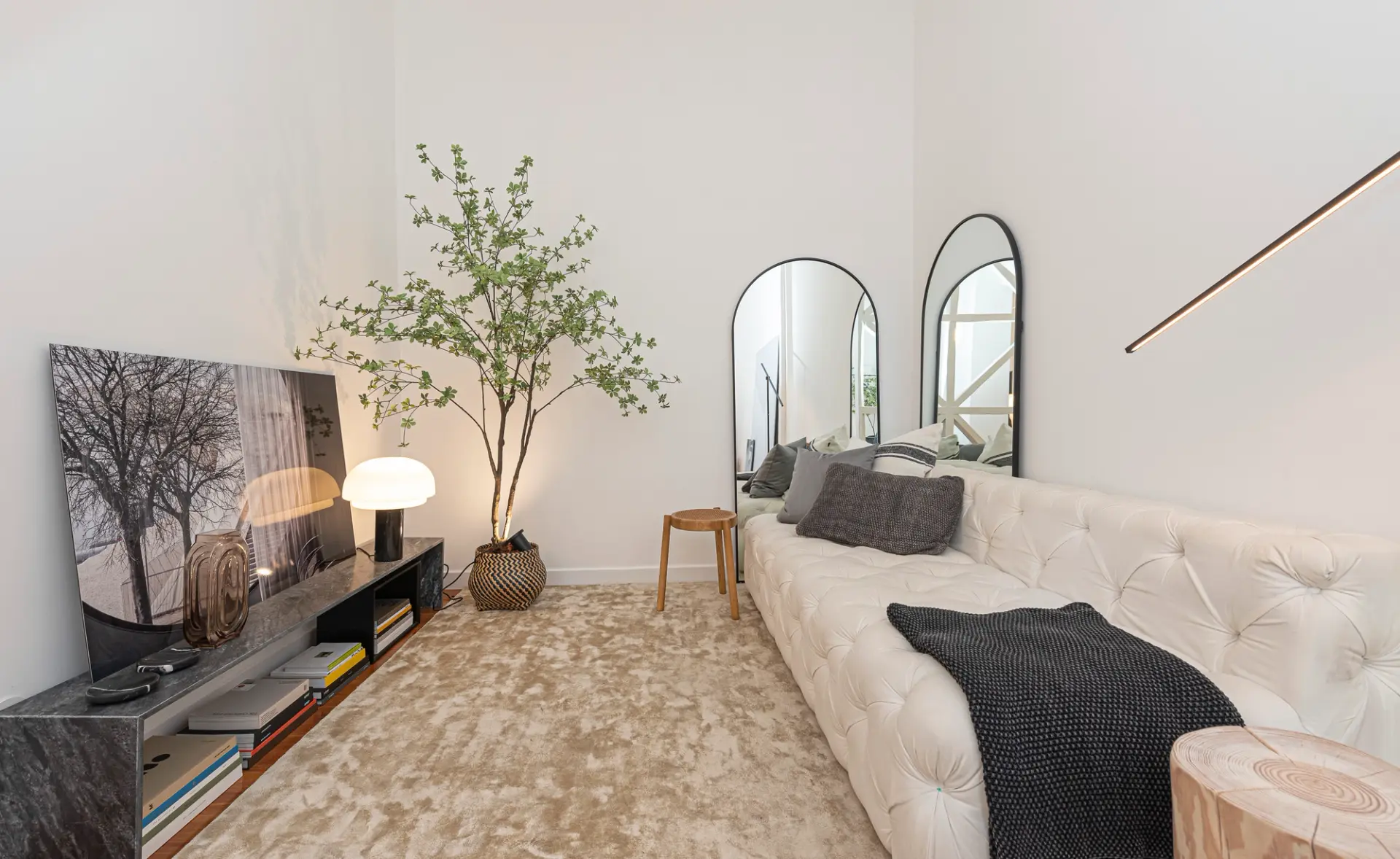 Sala de estar com sofá branco, espelhos, iluminação suspensa e mobiliário por medida, num projeto de design de interiores.
