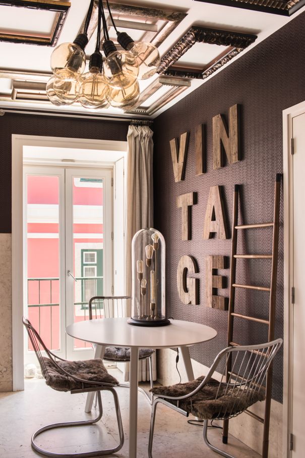 Eclectic dining area with statement lighting, decorative wall lettering and contemporary furniture.