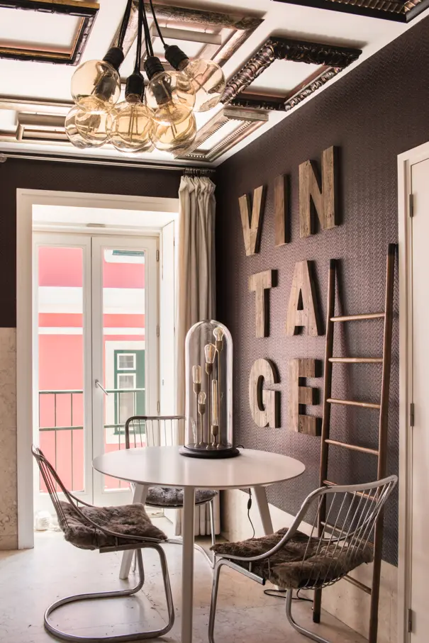 Eclectic dining area with statement lighting, decorative wall lettering and contemporary furniture.