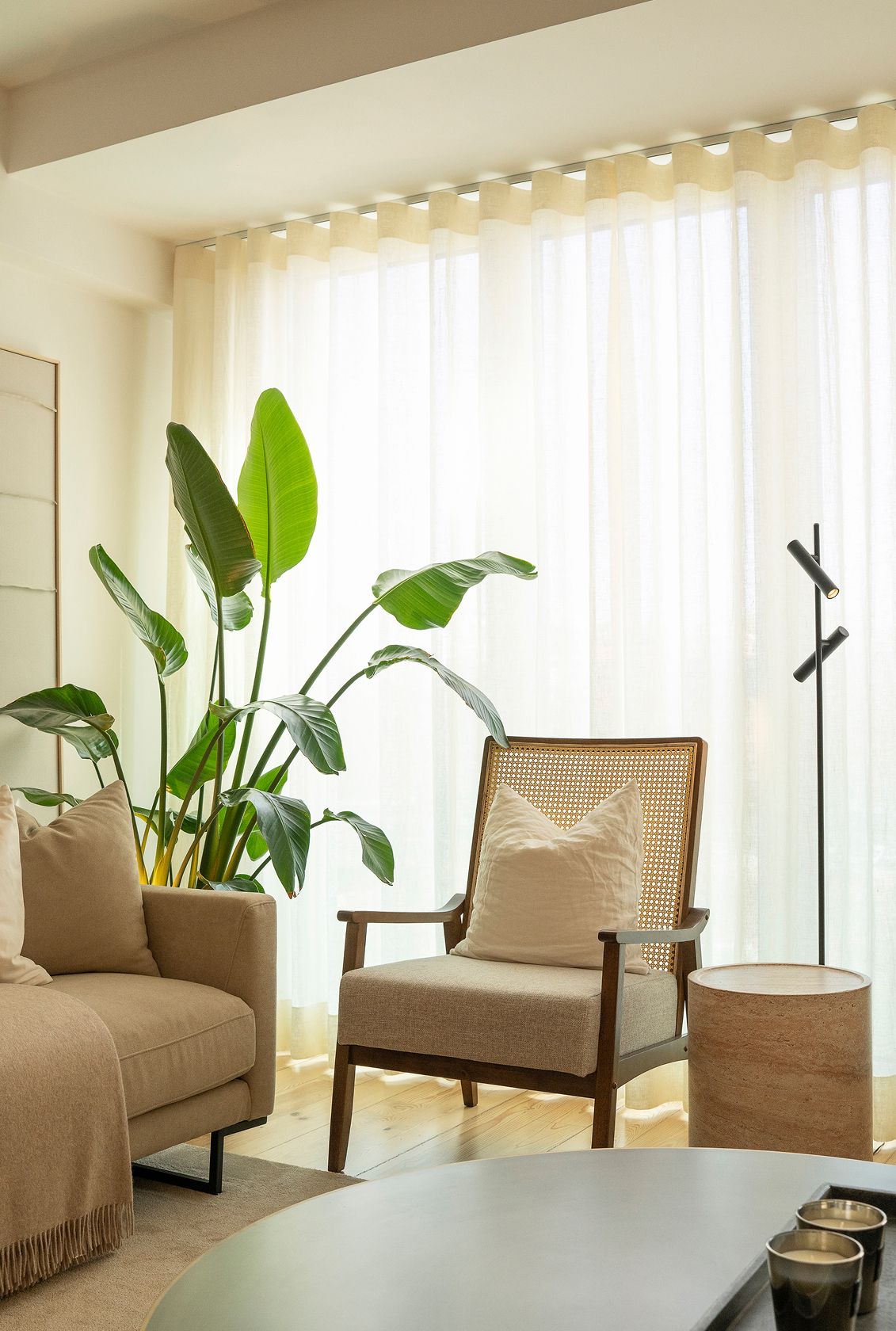 Walnut and cane armchair, cylindrical travertine side table and beige sofa — luxury décor details