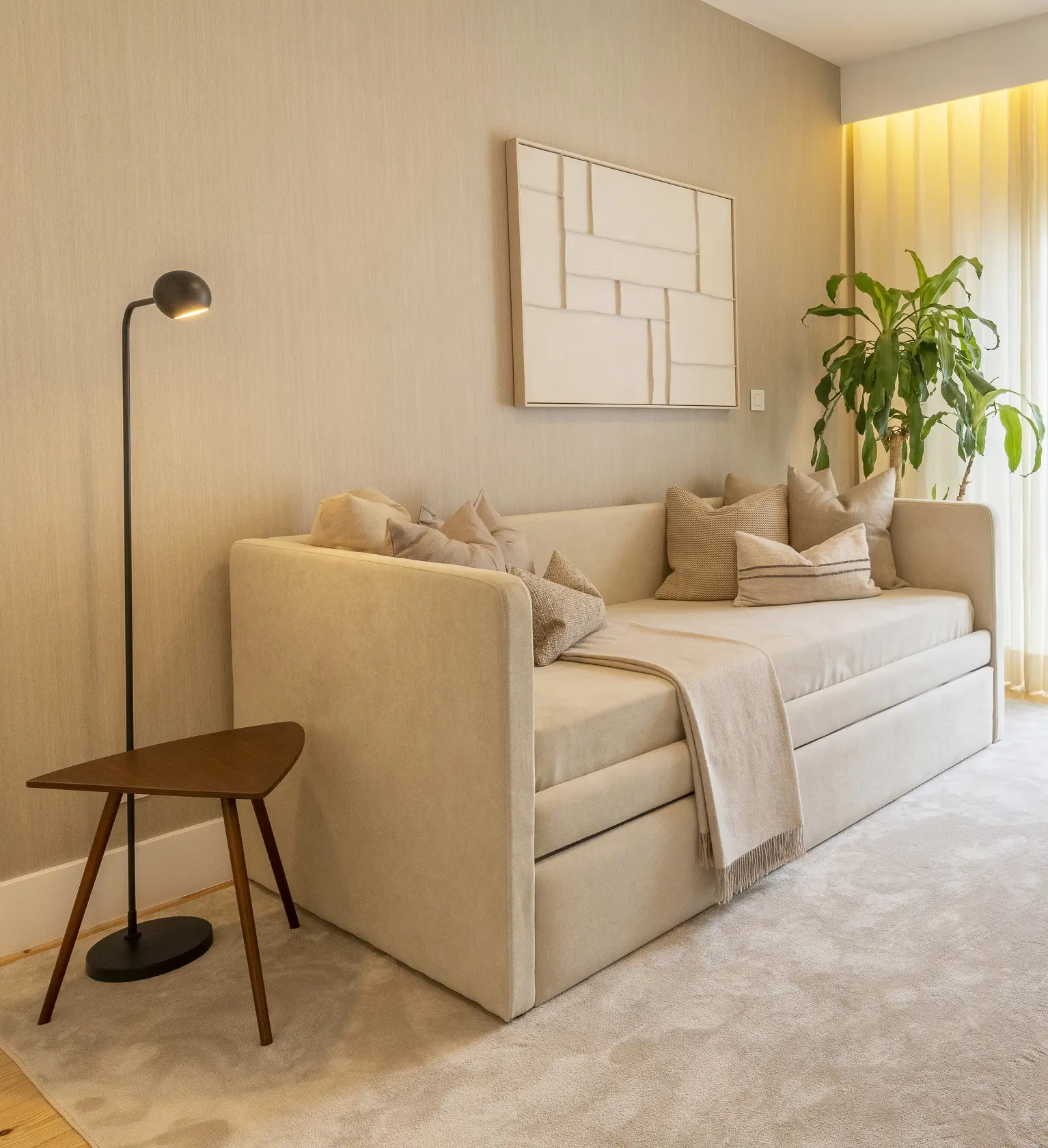 Cama individual estofada bege com candeeiro de pé globo preto e quadro de relevo branco sobre parede têxtil — quarto jovem de luxo
