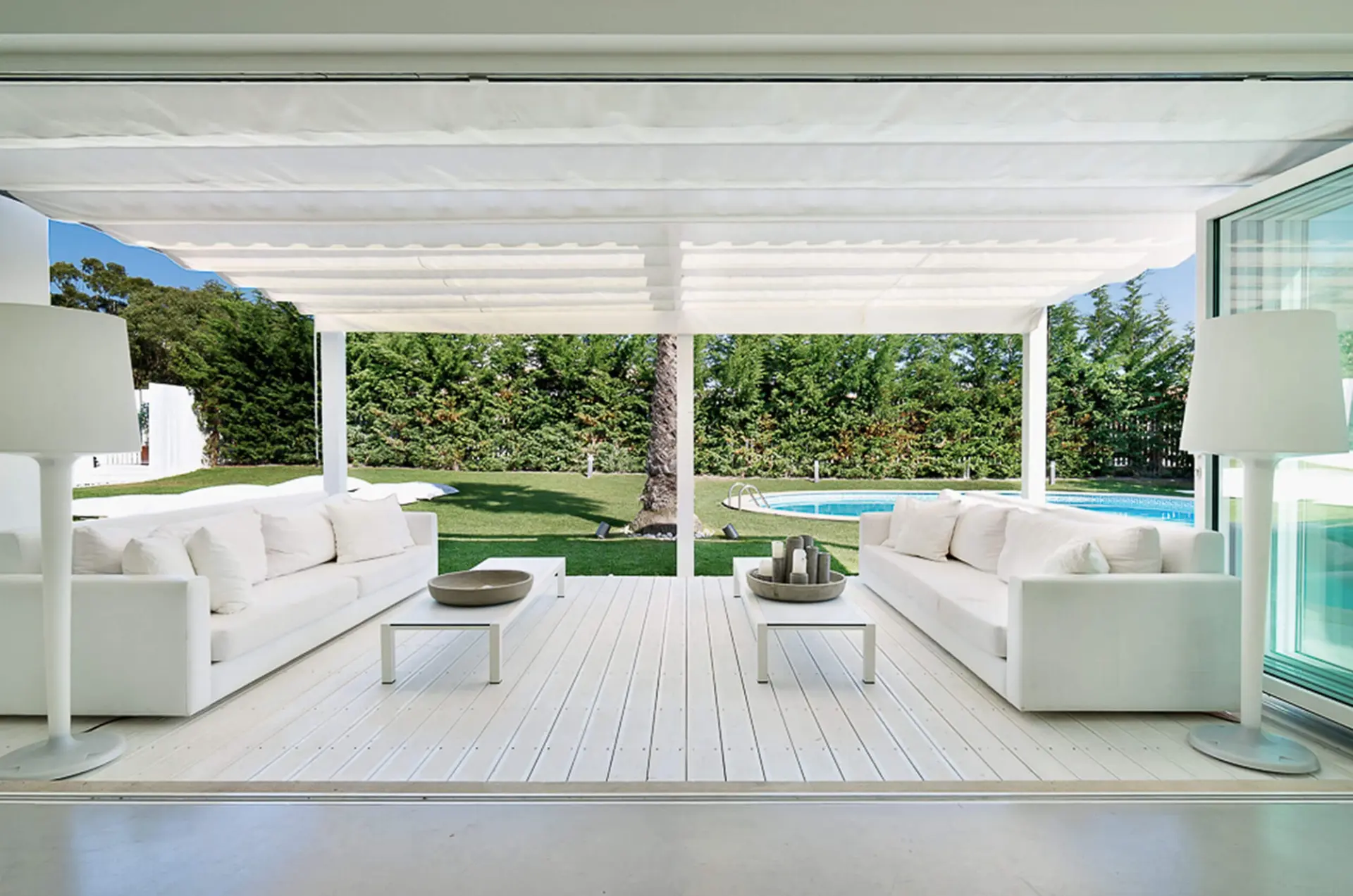 Esplanada coberta com pérgola, sofás brancos e deck com vista para jardim e piscina — design de interiores de luxo Tróia, Setúbal