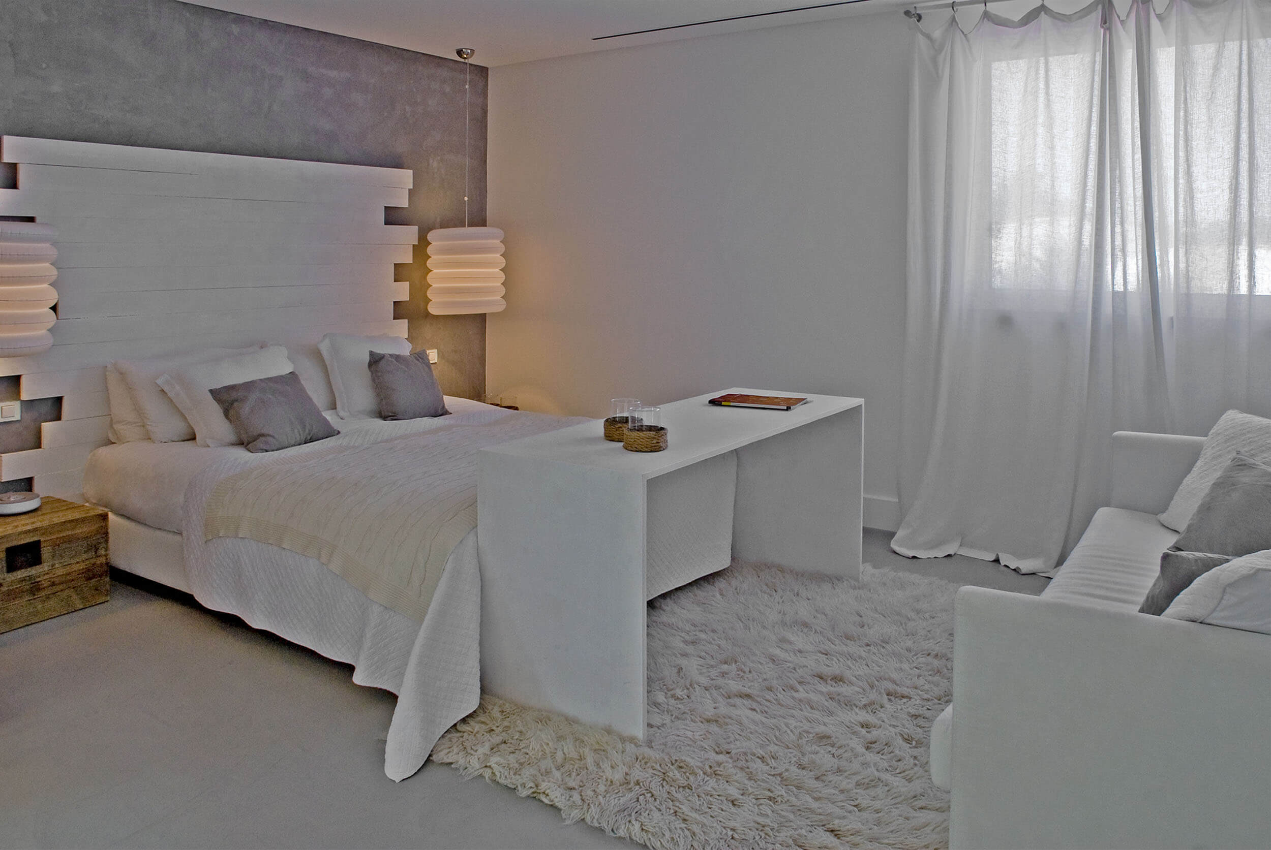 Quarto com cabeceira em ripado de madeira branca, parede em microcimento e tapete de pelo — design de interiores de luxo Tróia, Setúbal