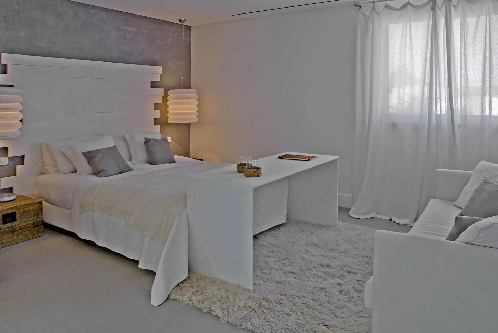 Quarto com cabeceira em ripado de madeira branca, parede em microcimento e tapete de pelo — design de interiores de luxo Tróia, Setúbal