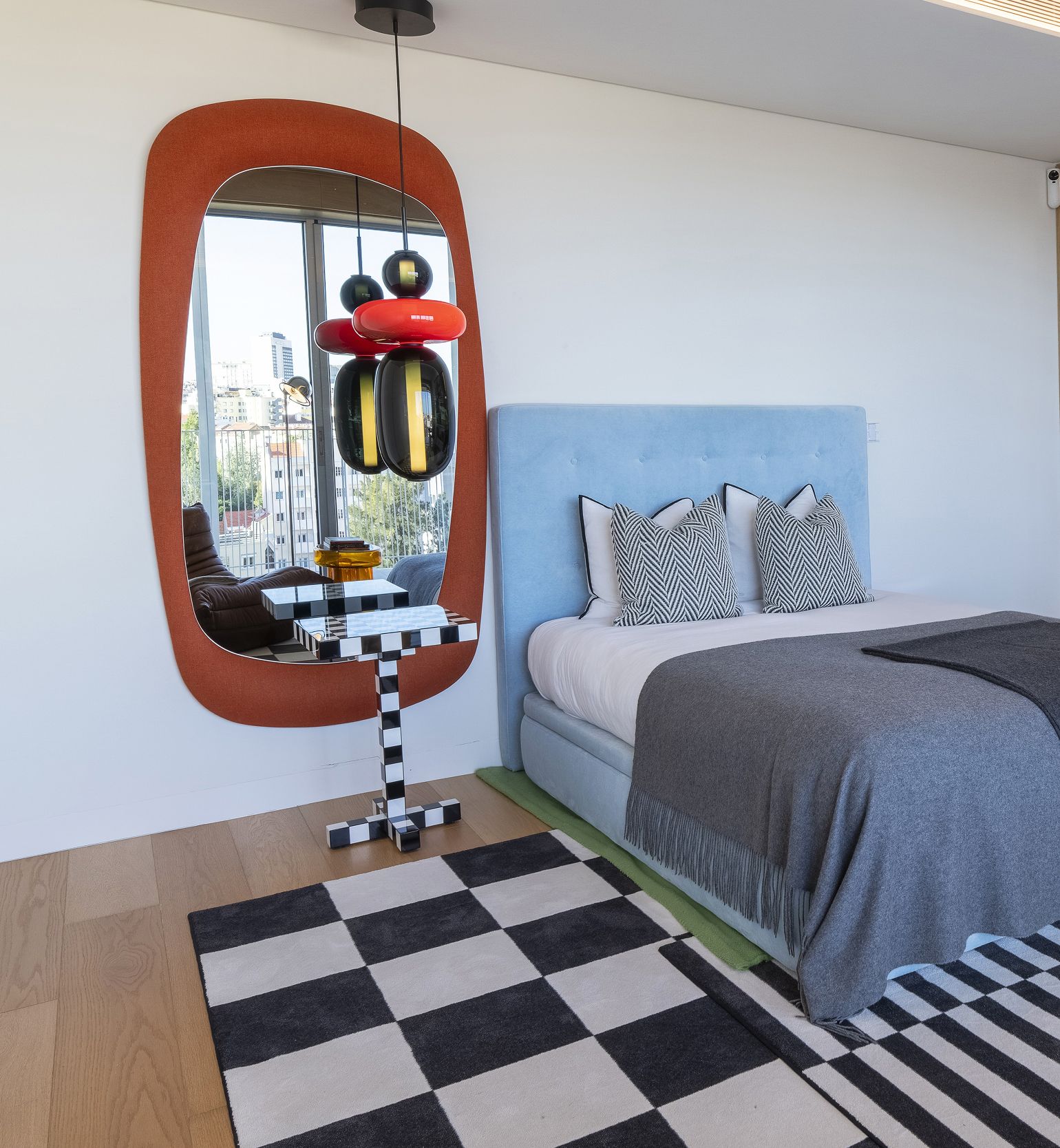 Quarto com espelho de moldura laranja, cabeceira azul e tapete xadrez preto e branco — design de interiores de luxo, Praça de Espanha, Atelier Renata Santos Machado