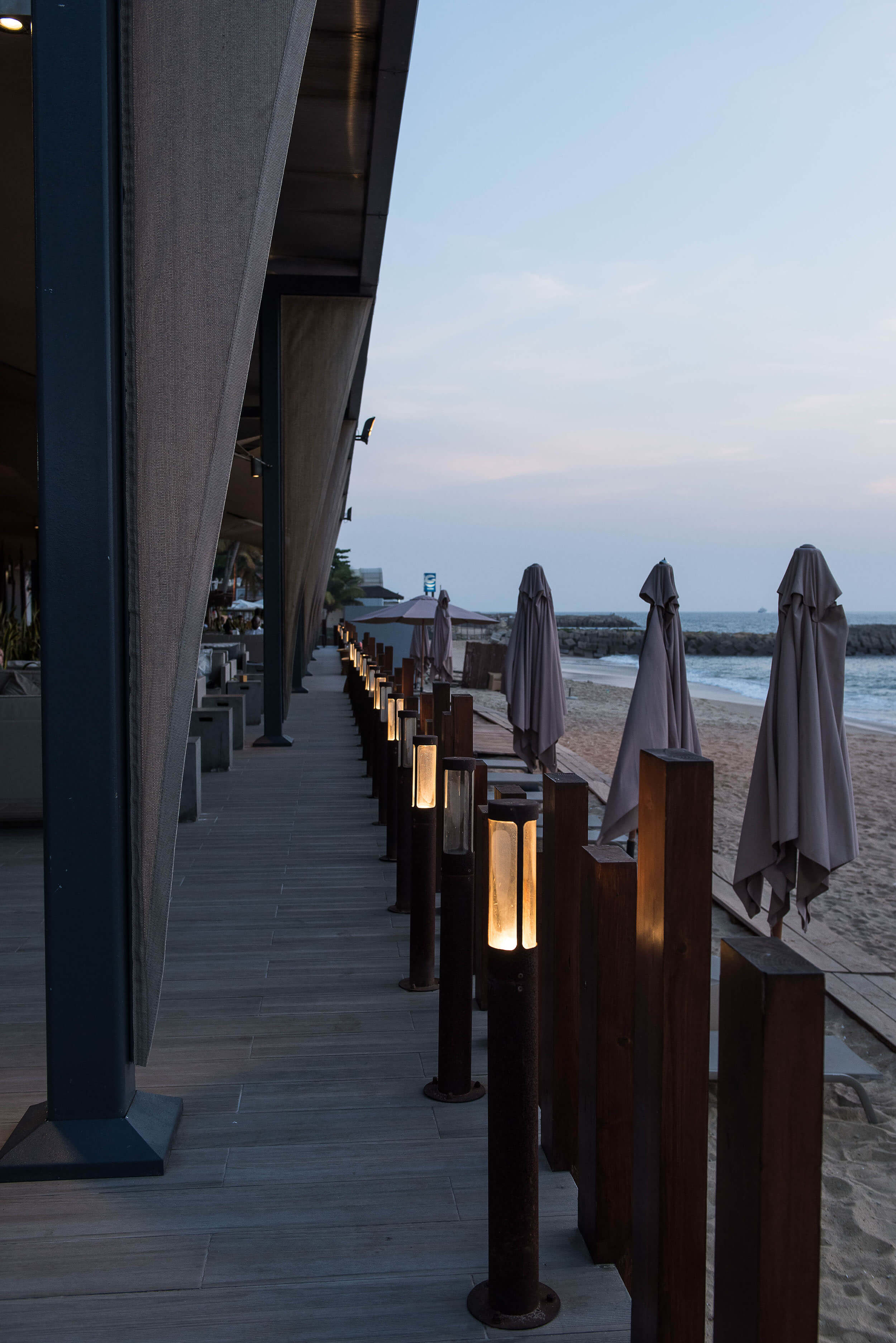 Deck à beira-mar com balizadores iluminados e chapéus de praia — design de interiores de restaurante de luxo Luanda, Angola