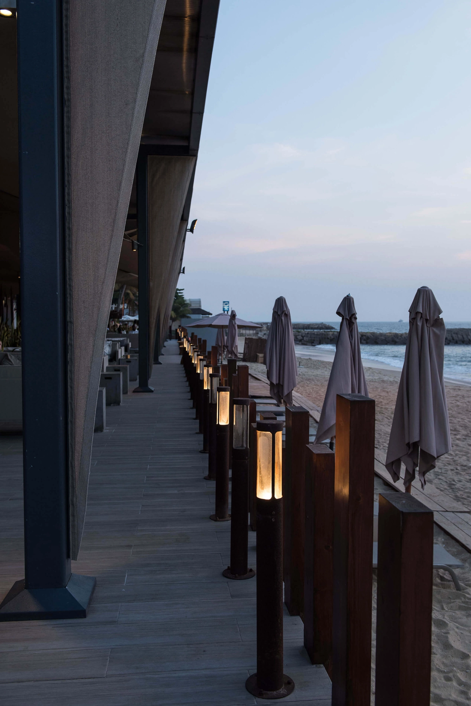 Deck à beira-mar com balizadores iluminados e chapéus de praia — design de interiores de restaurante de luxo Luanda, Angola
