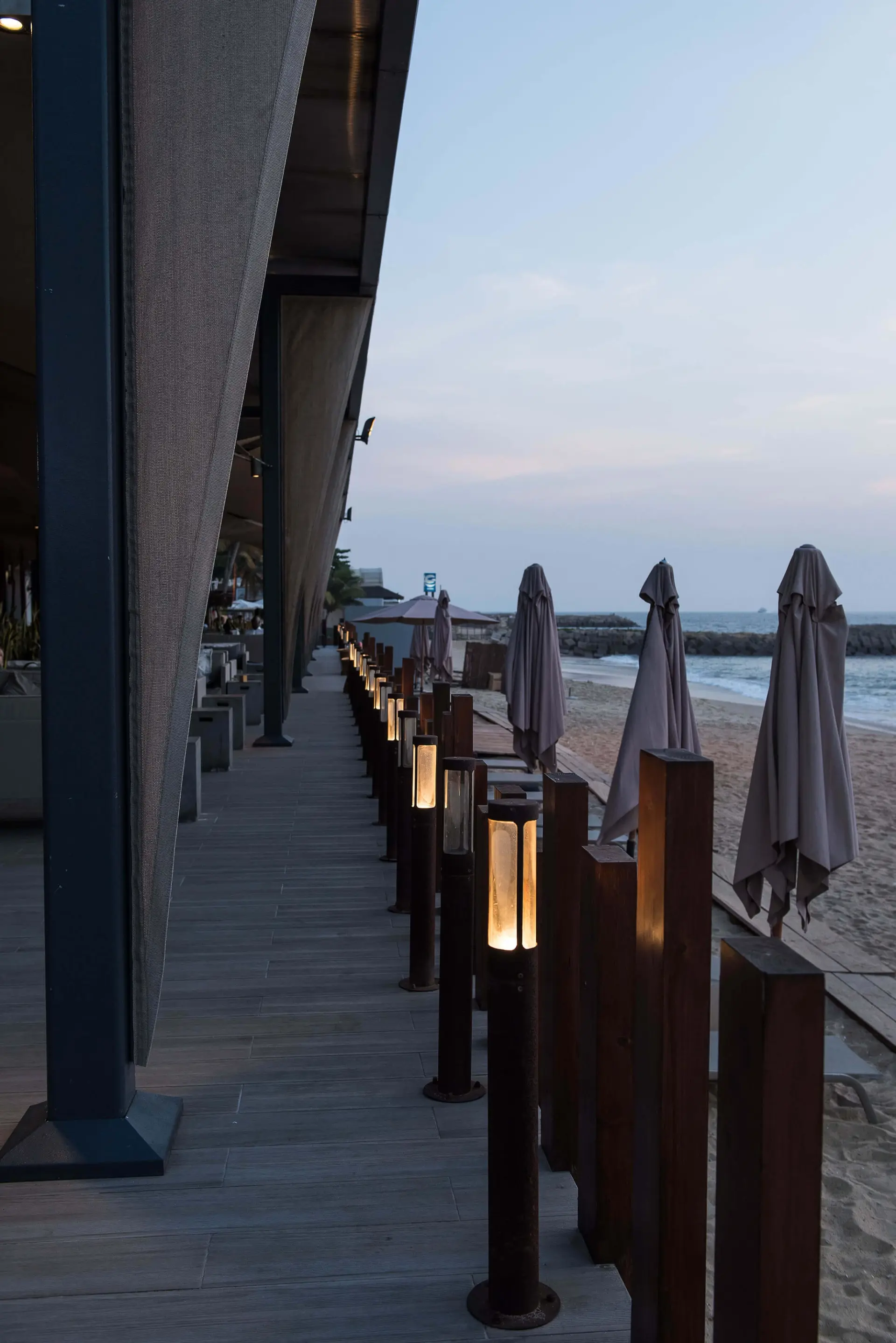 Deck à beira-mar com balizadores iluminados e chapéus de praia — design de interiores de restaurante de luxo Luanda, Angola