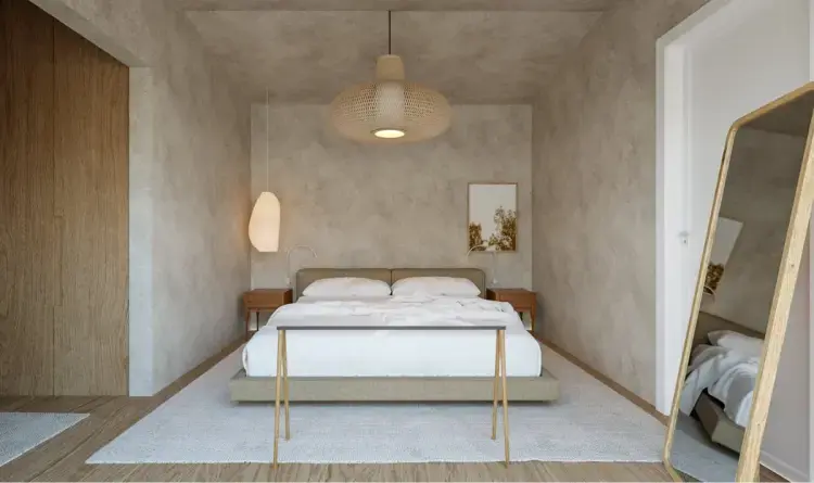 Quarto em tons neutros com cama de casal, mesas de cabeceira em madeira, candeeiros suspensos e espelho de corpo inteiro apoiado na parede.