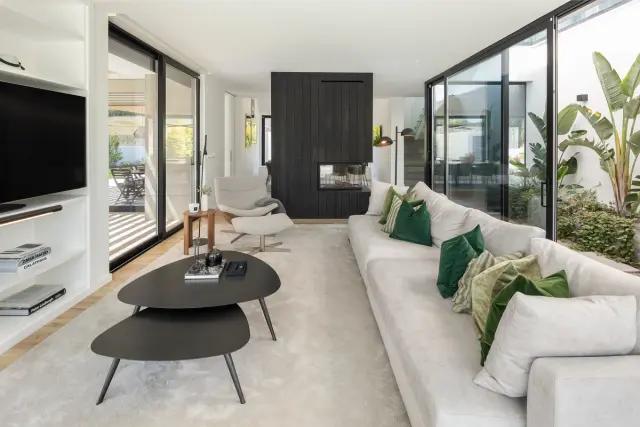 Living room with a white sofa, green accent pillows, nesting coffee tables, and floor-to-ceiling glass doors.