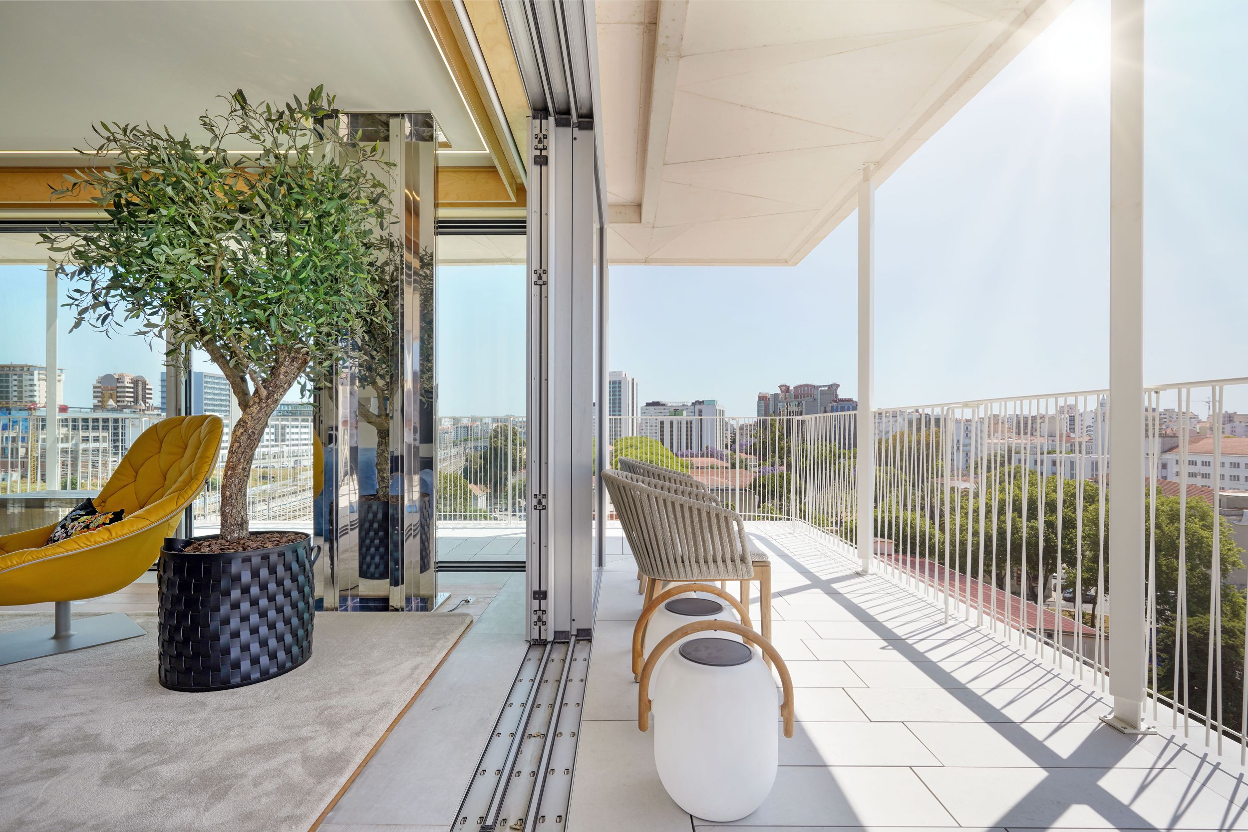 Terraço exterior com zona de estar, cadeira lounge, vegetação e ligação direta ao interior através de portas de vidro