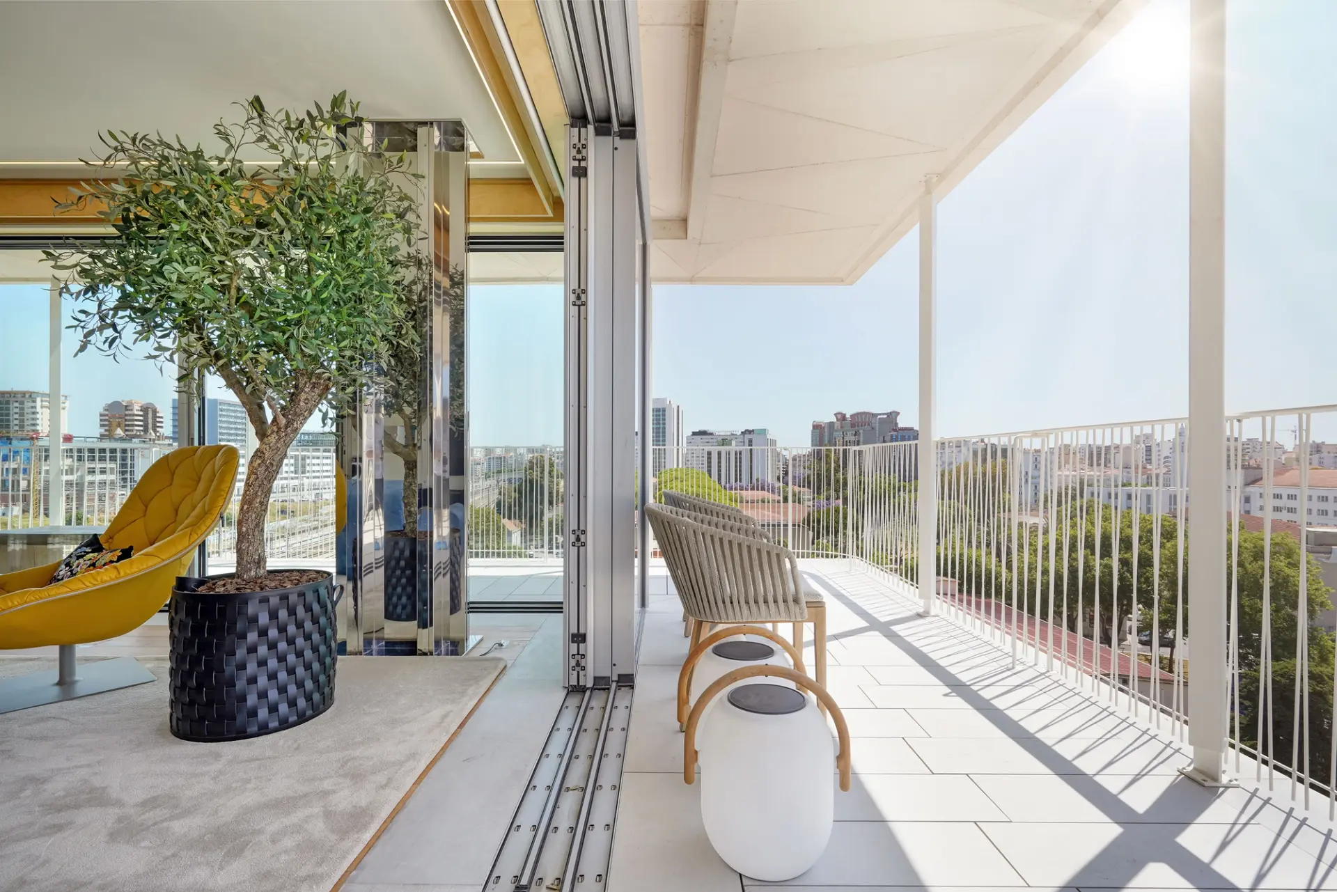 Terraço exterior com zona de estar, cadeira lounge, vegetação e ligação direta ao interior através de portas de vidro