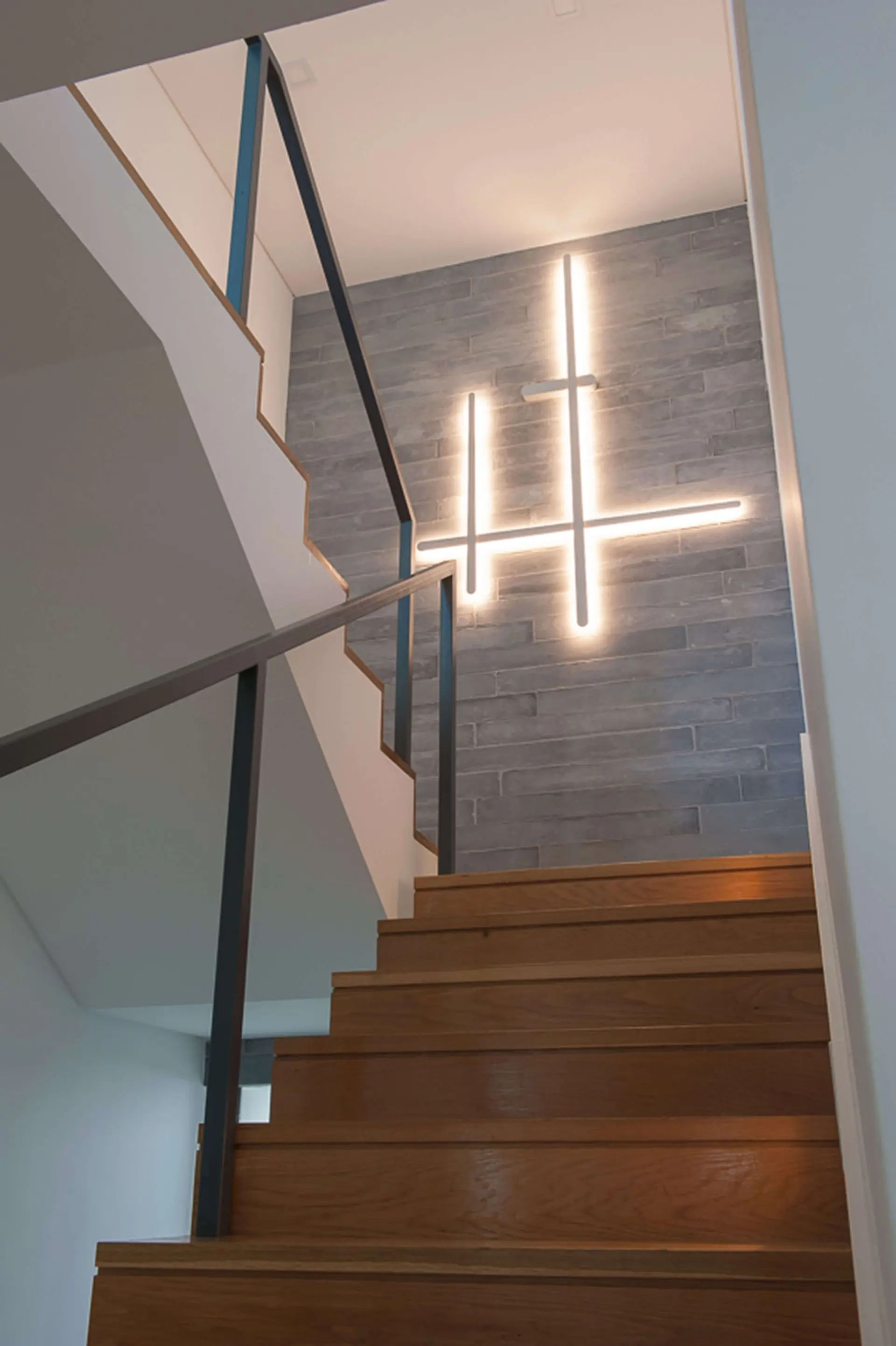 Escadaria com degraus madeira, revestimento pedra cinzenta e iluminação linear em cruz — design de interiores de luxo Paço de Arcos, Oeiras, Atelier Renata Santos Machado