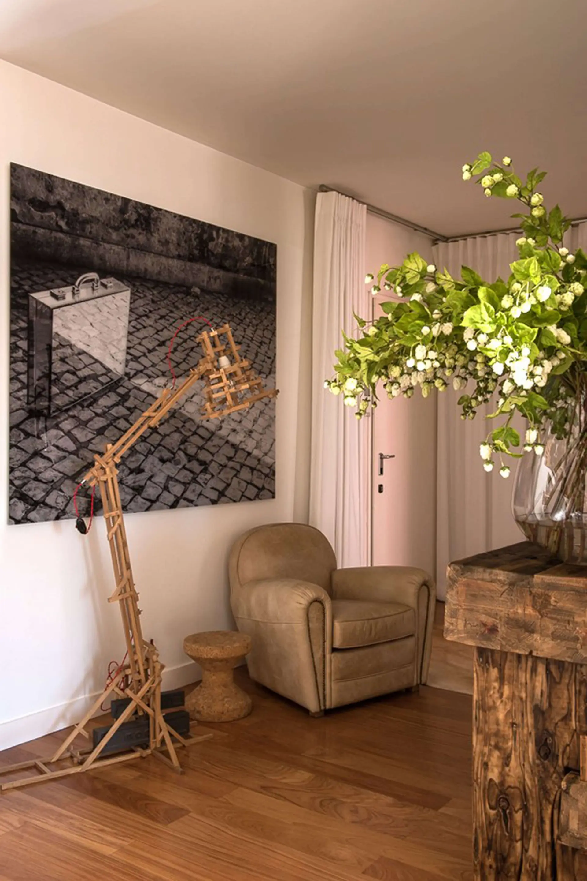 Articulated wooden floor lamp, cognac leather club armchair and a large urban black-and-white photograph — luxury entrance hall