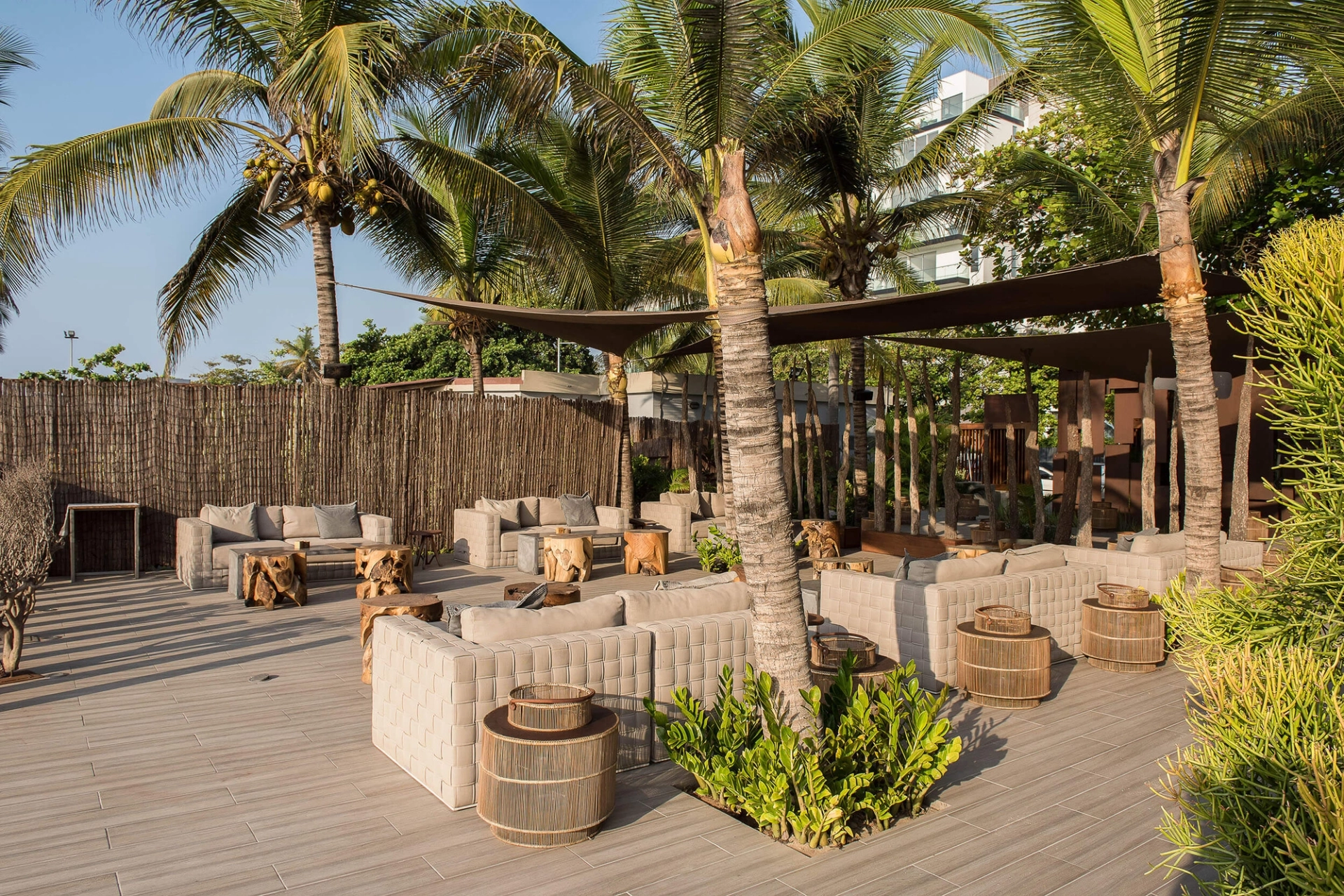 Lounge frente mar com palhota de colmo, toldos e mesas de rattan — design de interiores de restaurante de luxo Luanda, Angola