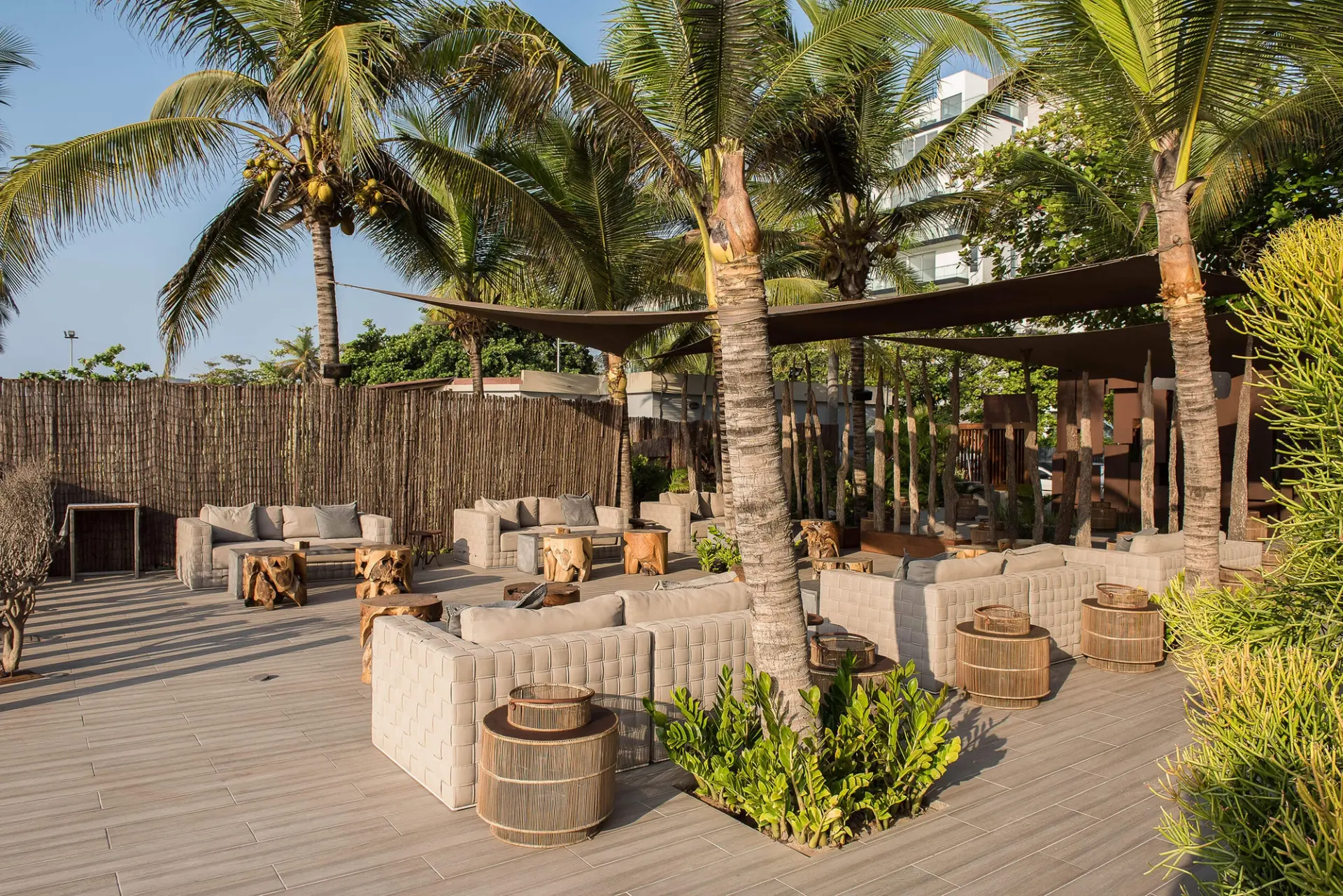 Lounge frente mar com palhota de colmo, toldos e mesas de rattan — design de interiores de restaurante de luxo Luanda, Angola