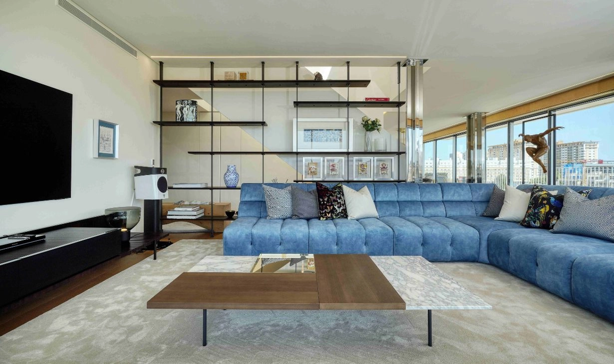 Contemporary living room interior design project in Lisbon by Atelier Renata Santos Machado, featuring a blue modular sofa, custom shelving and panoramic city views.