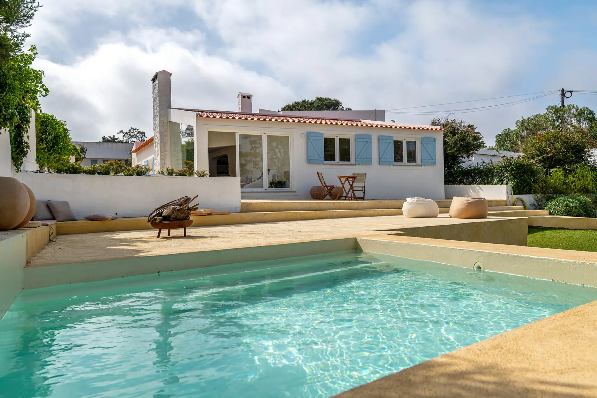 Exterior de moradia remodelada com piscina e zona de lazer, num projeto de design de interiores.