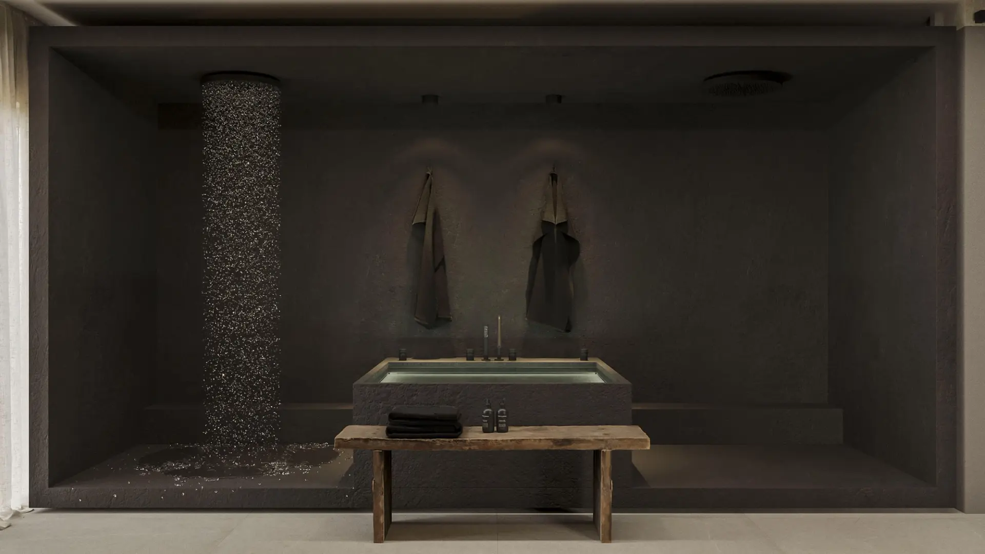 Recessed tub in dark microcement with a pebble shower column, a rustic wood bench and hanging towels — luxury bathroom