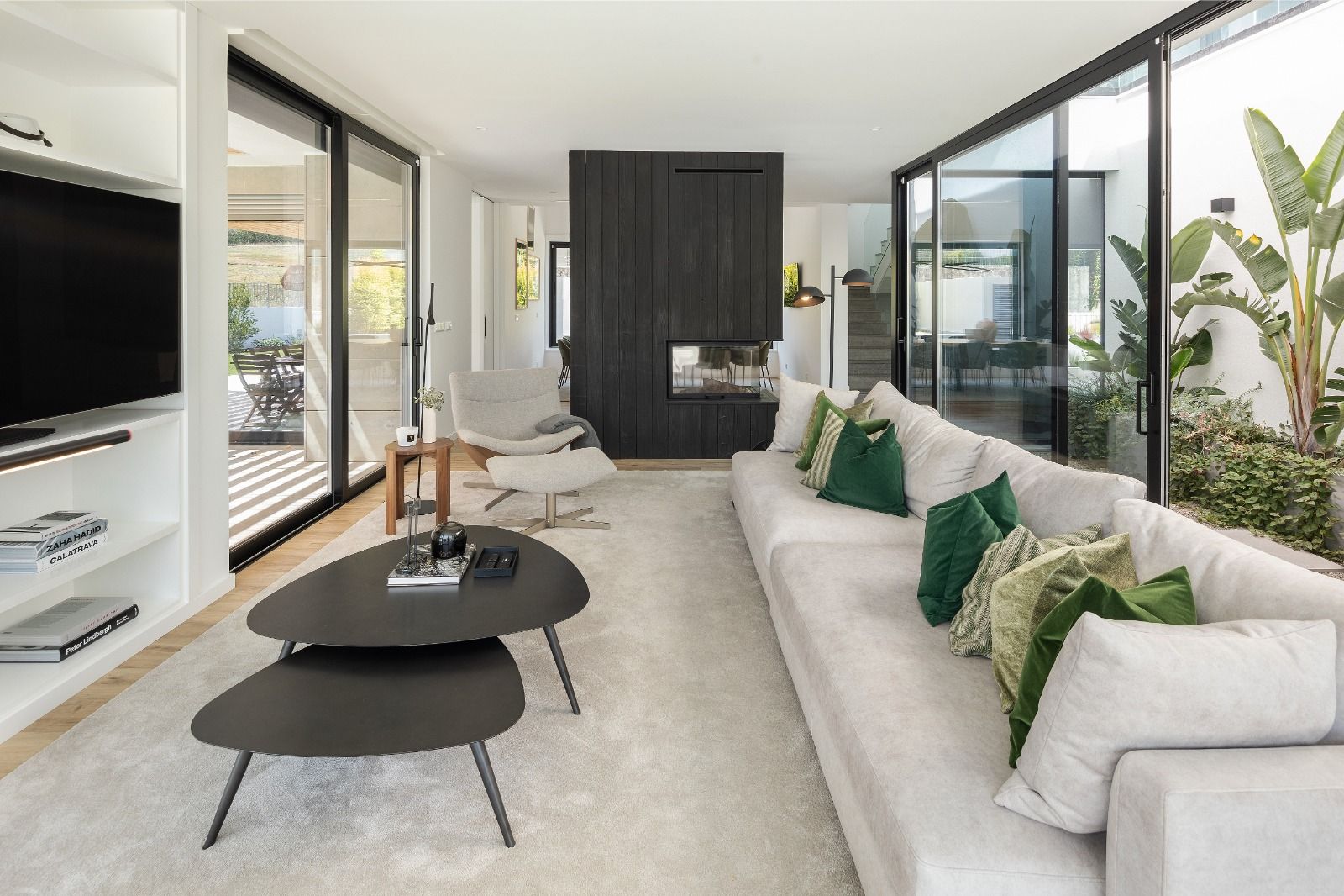 Sala contemporânea projetada pelo Atelier Renata Santos Machado com lareira central, luz natural abundante e ligação ao exterior.