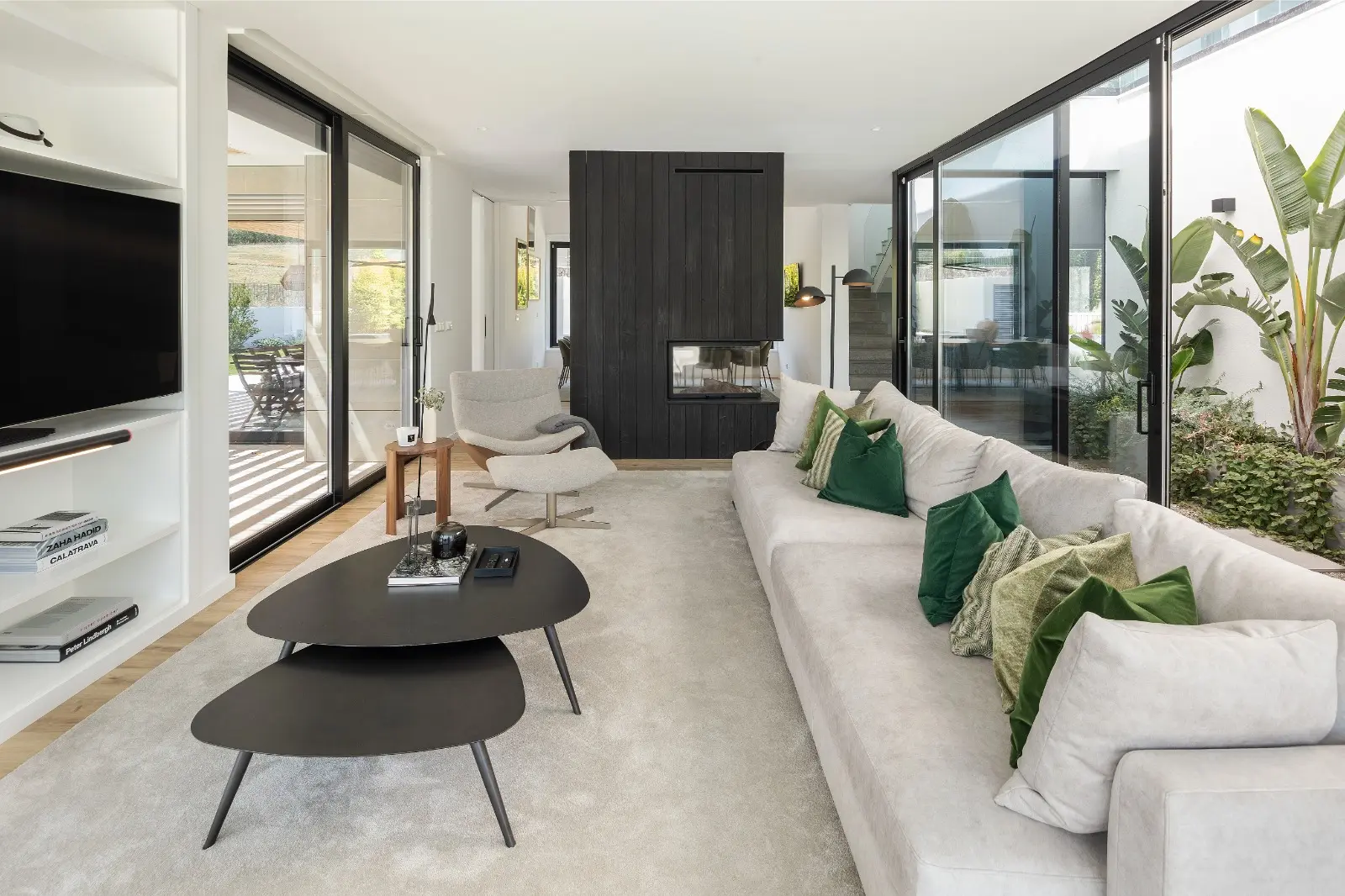 Sala contemporânea projetada pelo Atelier Renata Santos Machado com lareira central, luz natural abundante e ligação ao exterior.