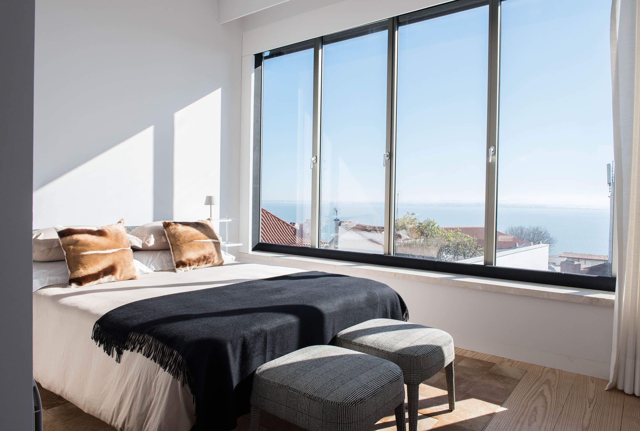 Master bedroom with Flexform bed, cognac leather cushion and panoramic Tagus River views — luxury interior design, Lisbon, Atelier Renata Santos Machado