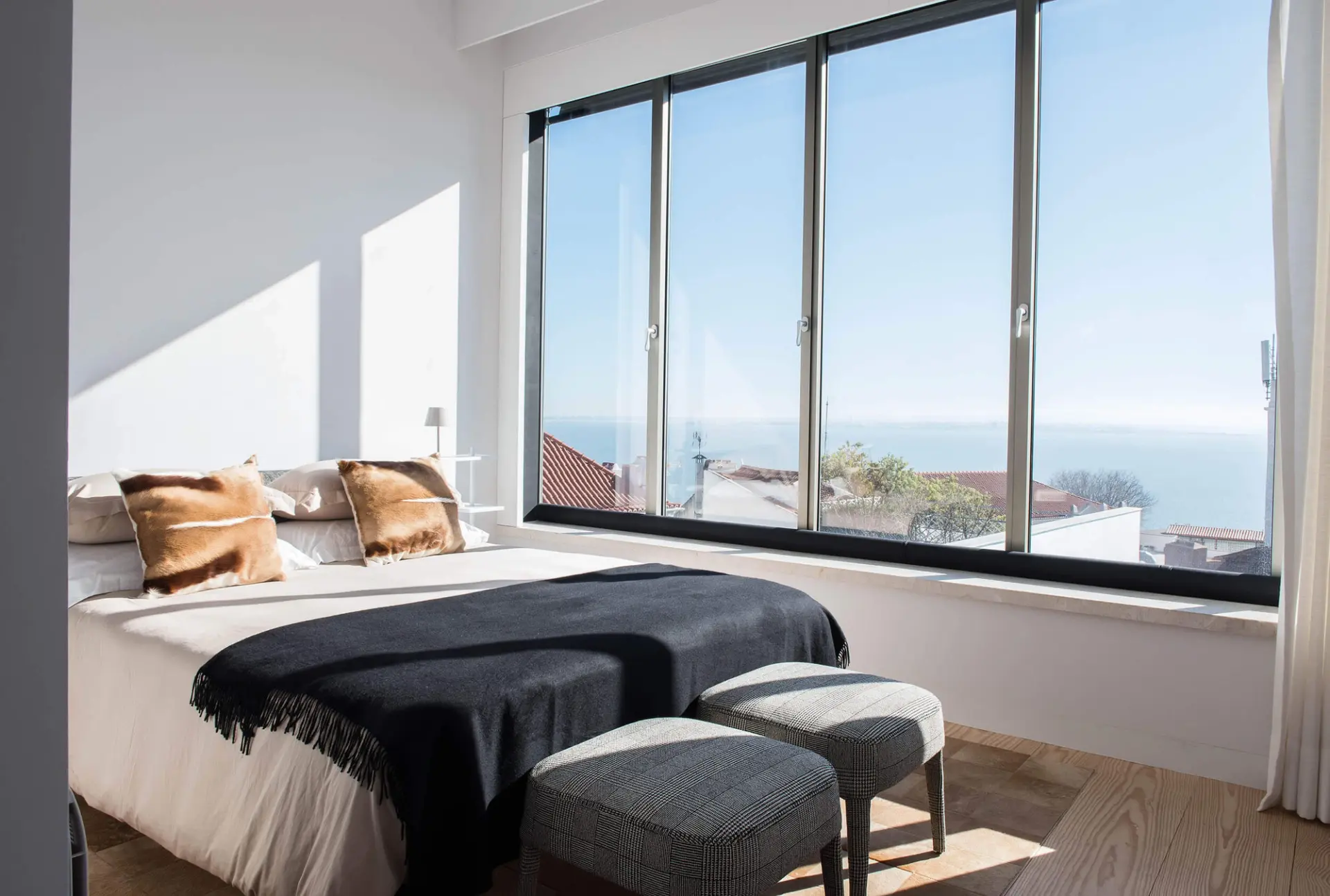 Master suite com cama Flexform, almofada em pele cognac e vista panorâmica sobre o Tejo — design de interiores de luxo, Lisboa, Atelier Renata Santos Machado