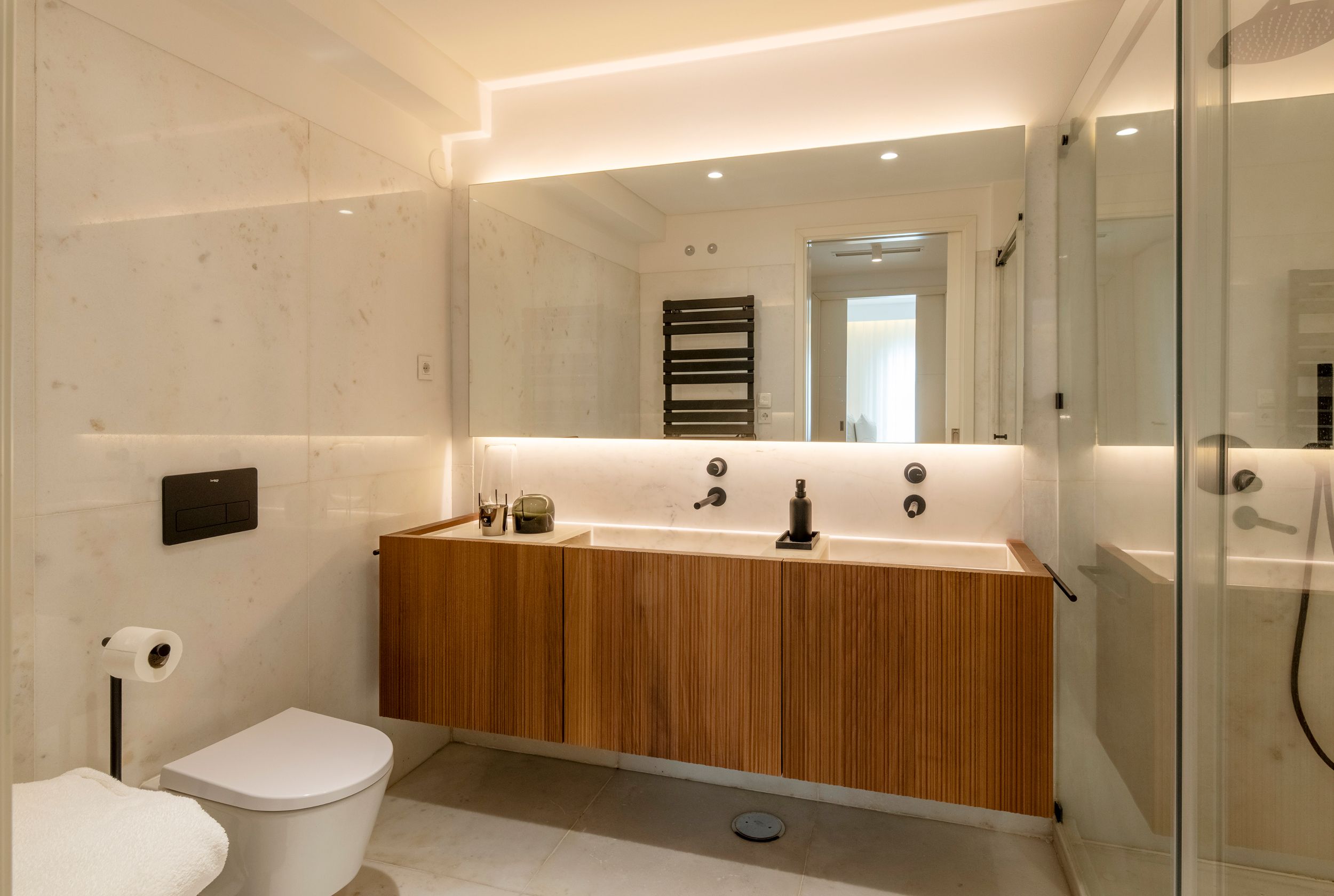 Casa de banho moderna com design de interiores em Lisboa, com iluminação integrada, madeira e acabamento contemporâneo