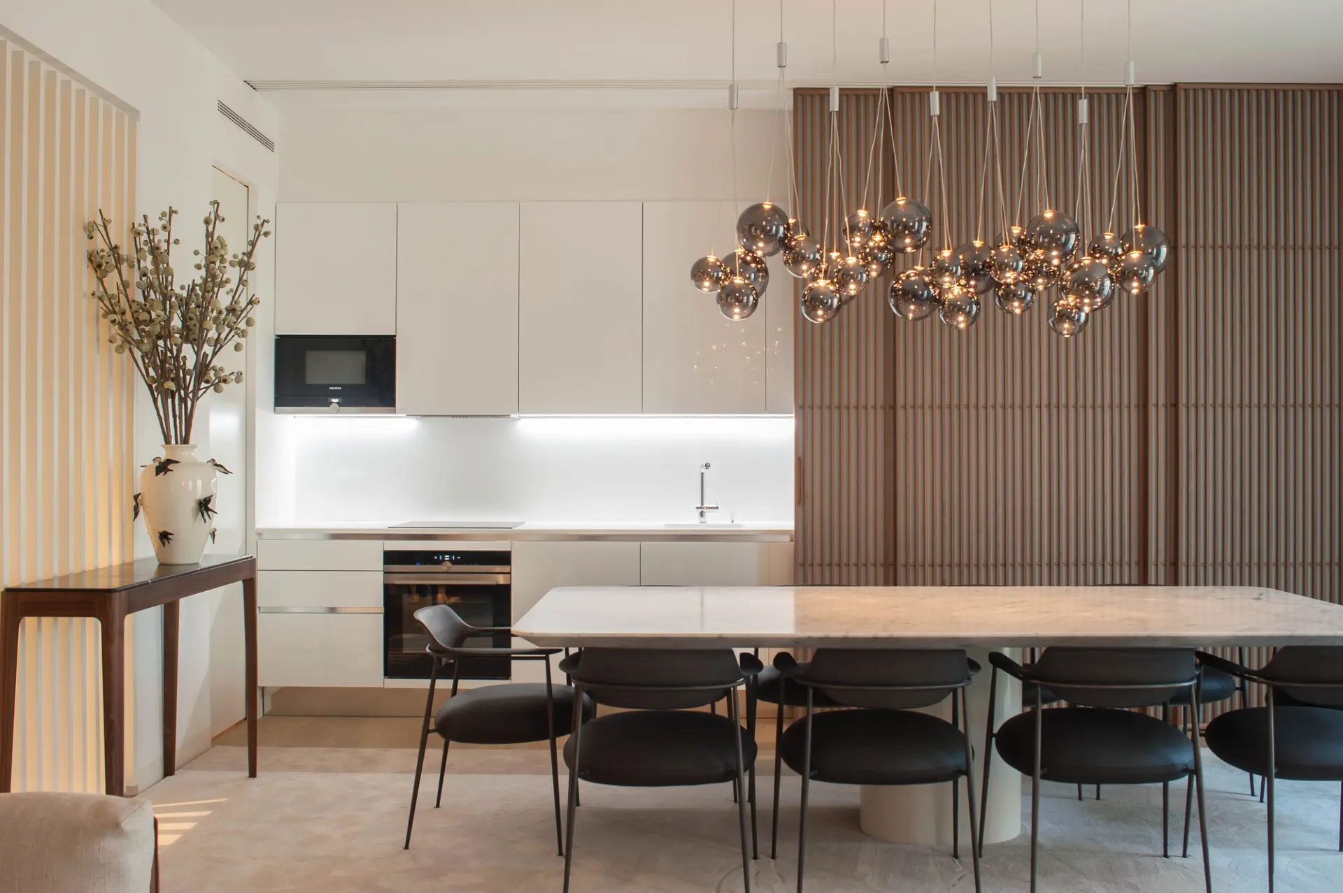 Projeto de remodelação em Lisboa com cozinha aberta para a sala de jantar, mobiliário por medida e iluminação suspensa.