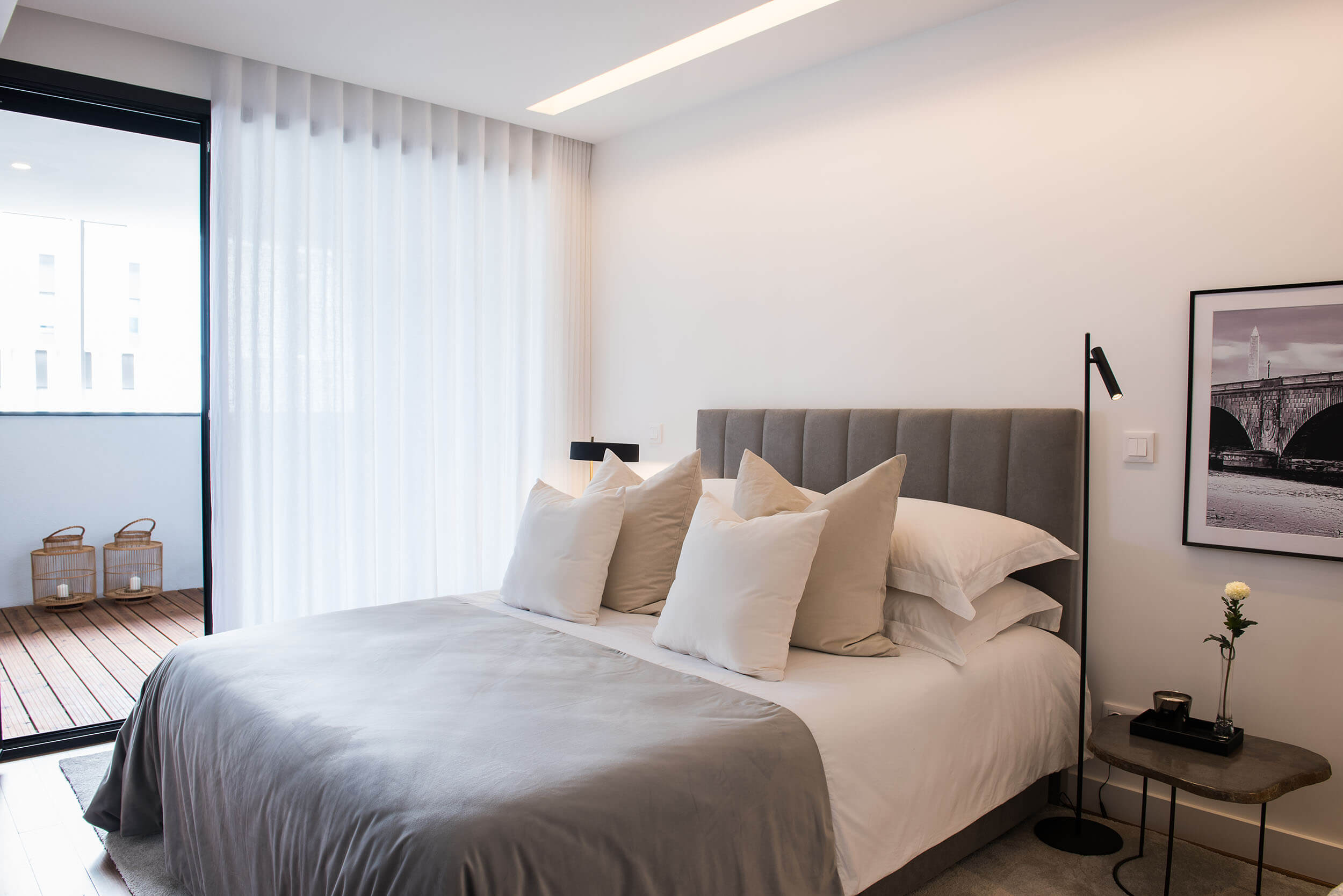 Grey channel-tufted headboard, black reading floor lamp and stone bedside table — luxury master suite design