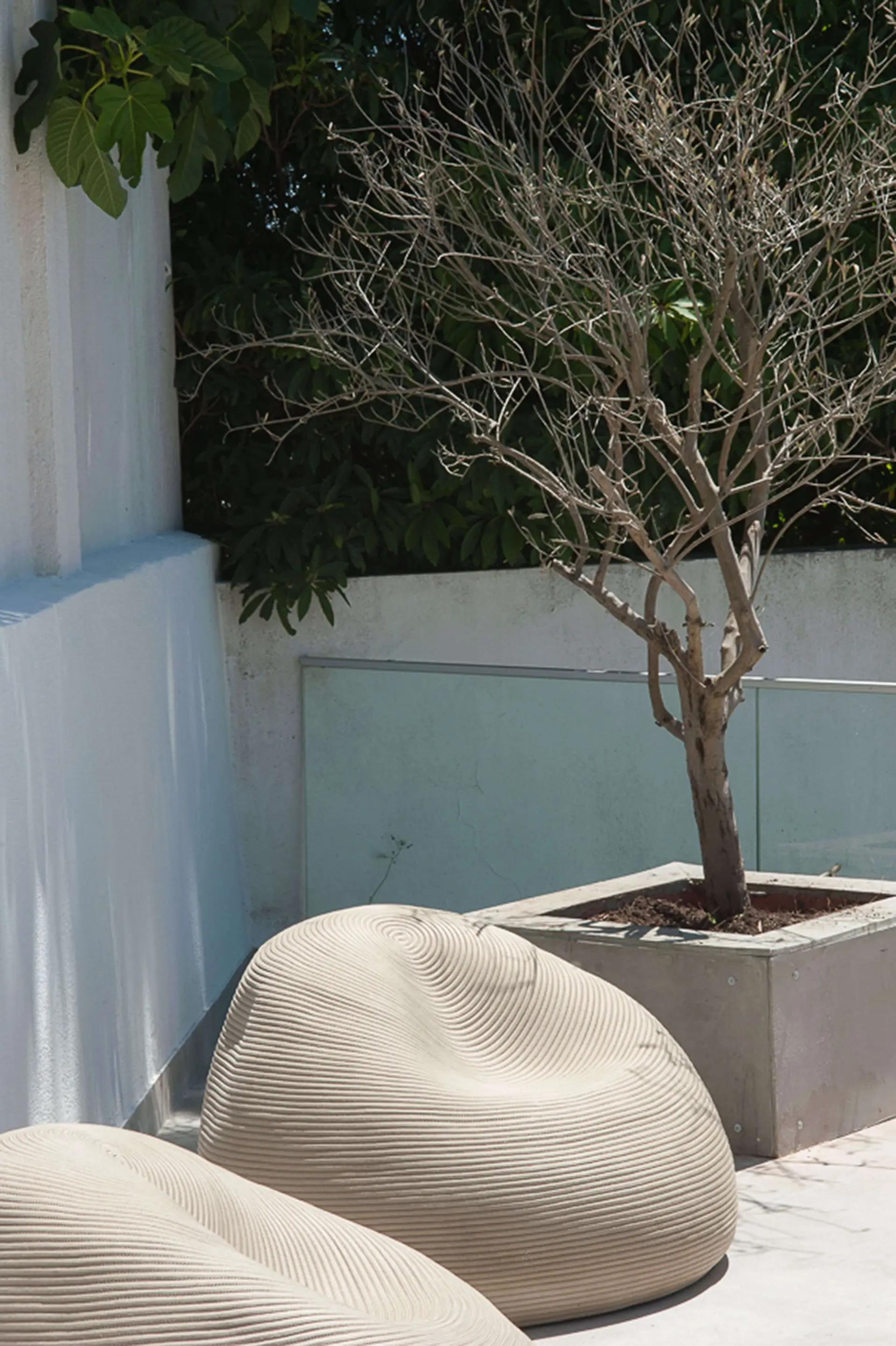 Terraço exterior com dois poufs orgânicos trançados ivory e oliveira em vaso branco — design de interiores de luxo Paço de Arcos, Oeiras, Atelier Renata Santos Machado