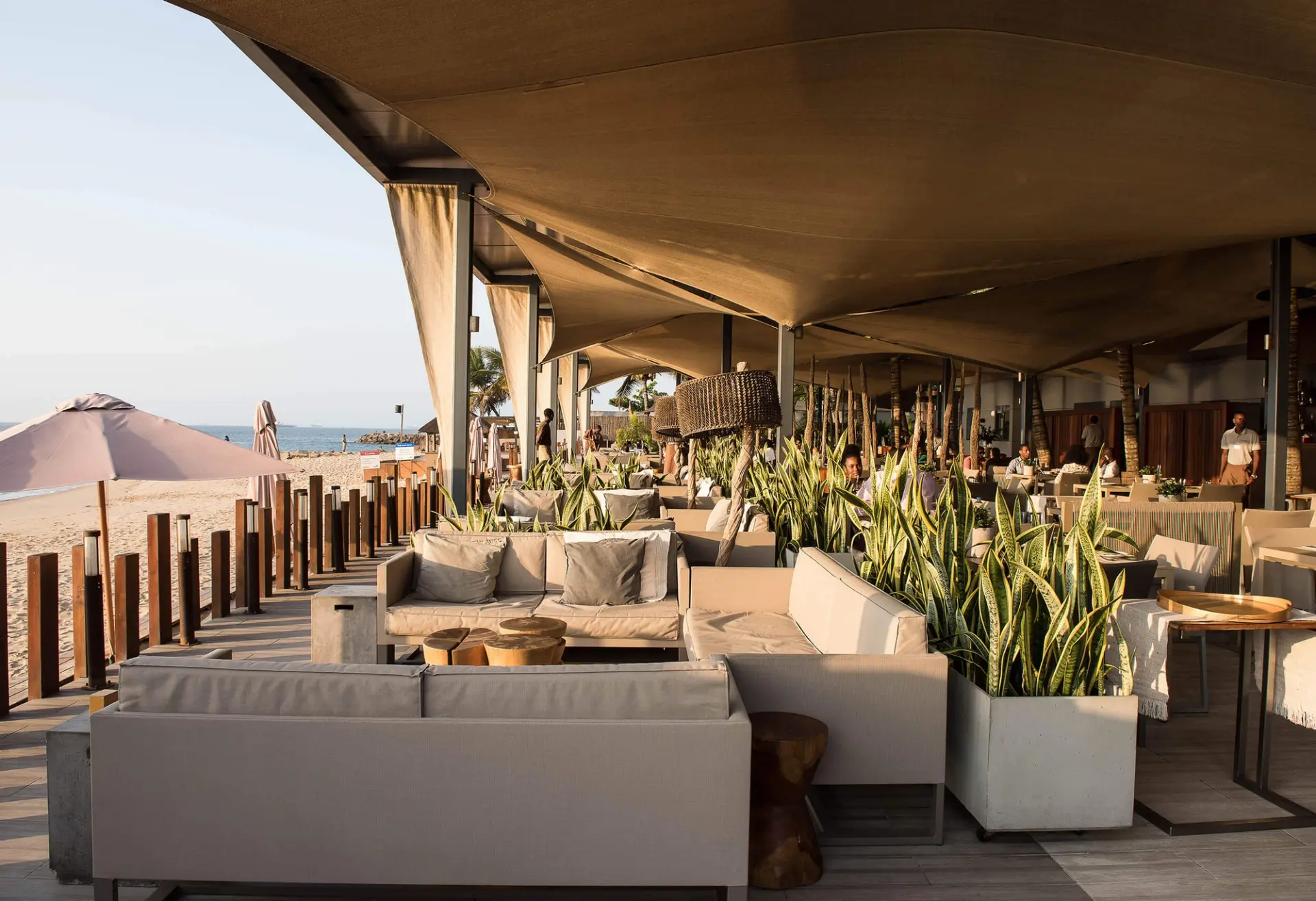 Lounge com cadeirões em corda trançada, bar e troncos de palmeira — design de interiores de restaurante de luxo Luanda, Angola