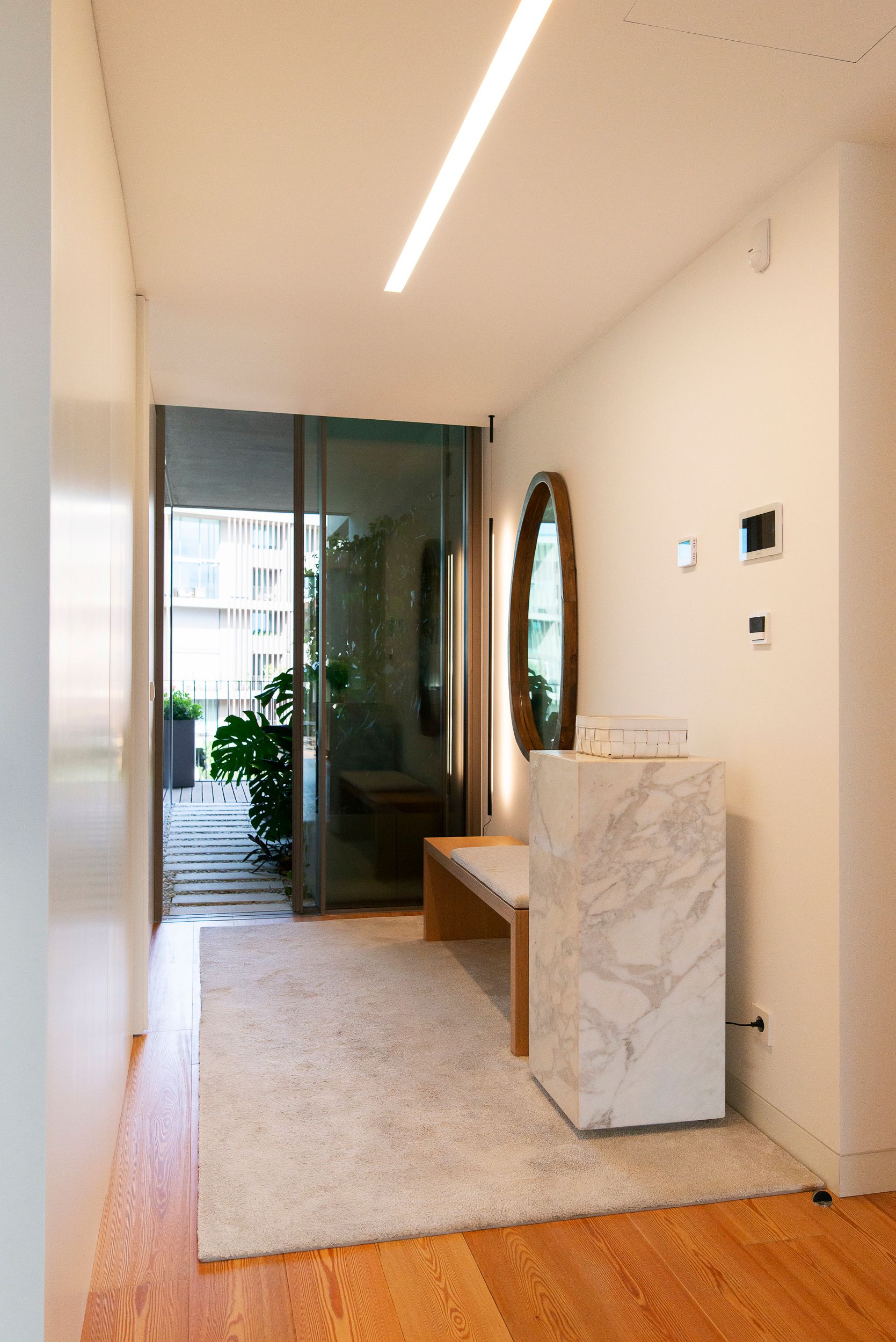 Hall de entrada com móvel em pedra, espelho e iluminação integrada num projeto de design de interiores.