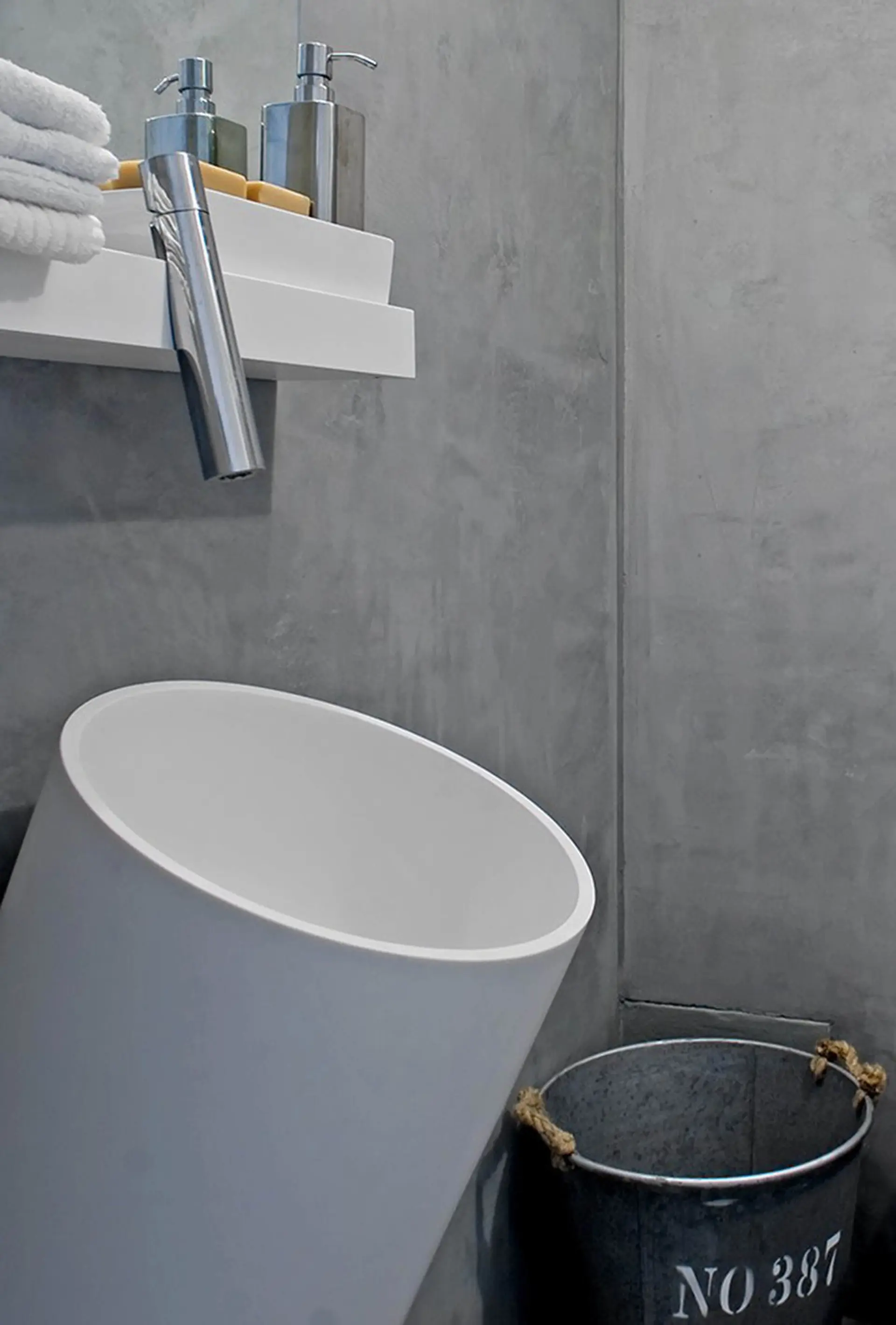 Casa de banho em microcimento com lavatório cilíndrico de topo angulado e prateleira suspensa — design de interiores de luxo Tróia, Setúbal