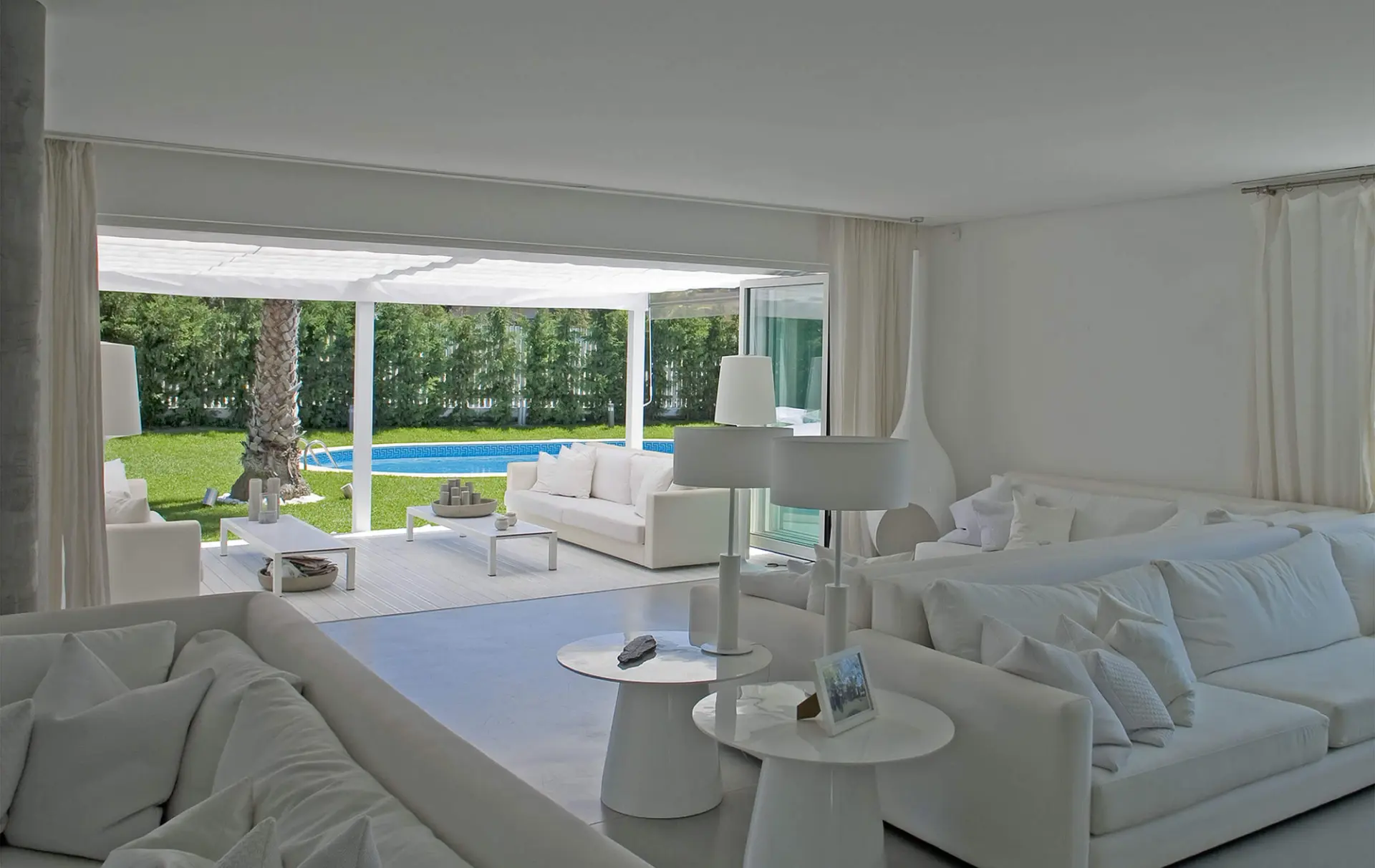 Sala de estar branca com sofás amplos e abertura para esplanada com piscina — design de interiores de luxo Tróia, Setúbal
